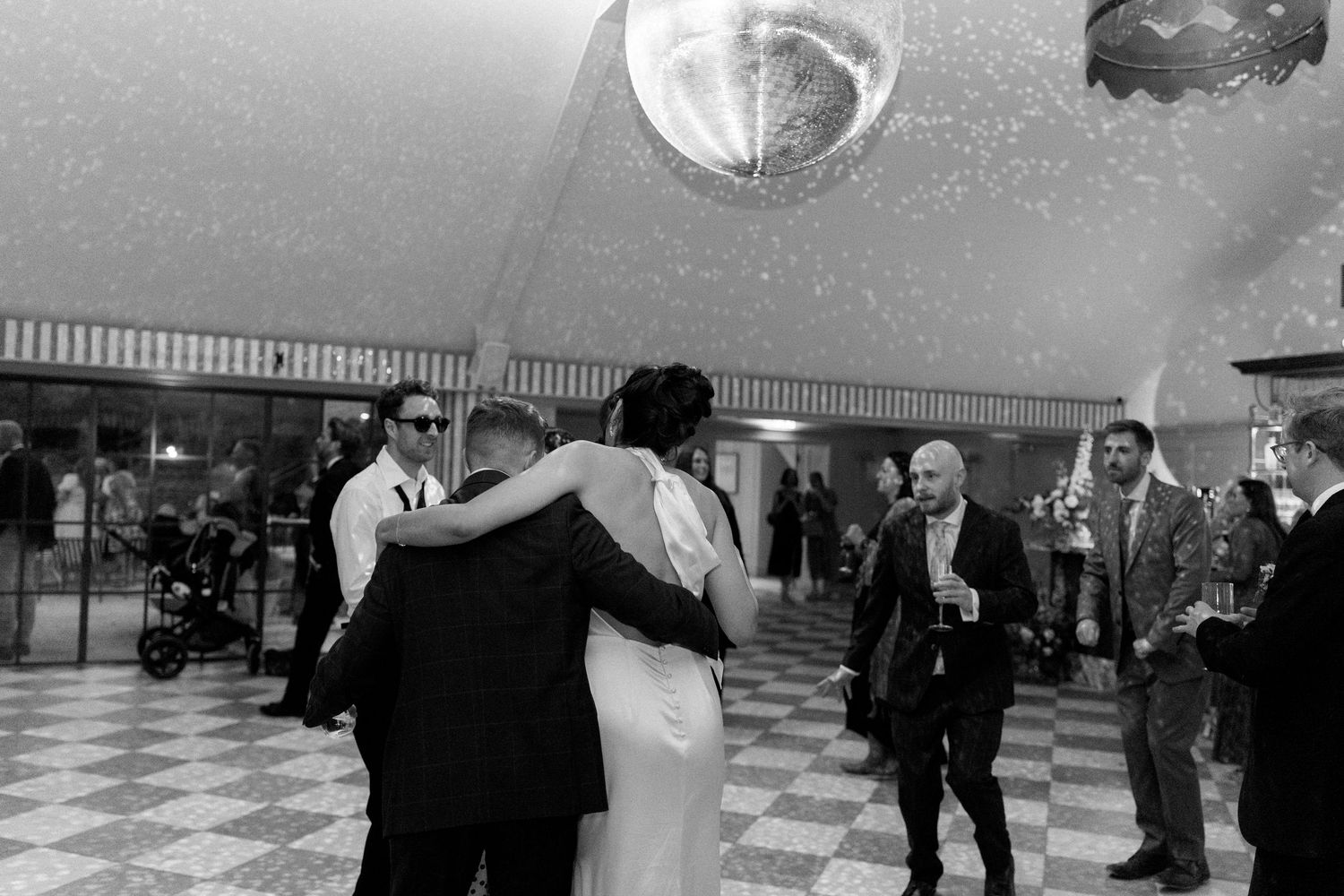 Bride and groom sharing a romantic dance under a disco ball at their elegant wedding reception.
