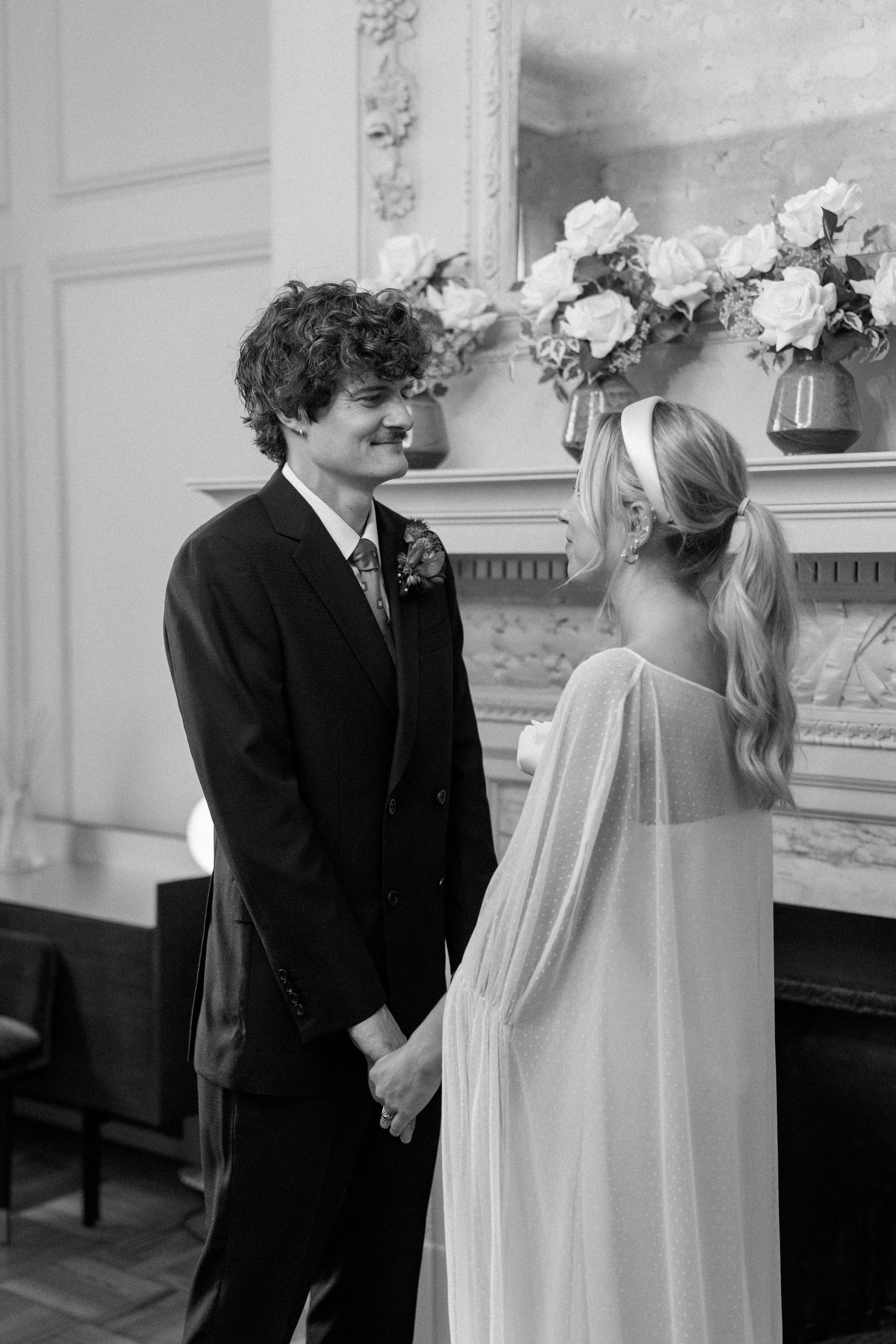 Intimate wedding ceremony moment captured in front of an ornate fireplace.