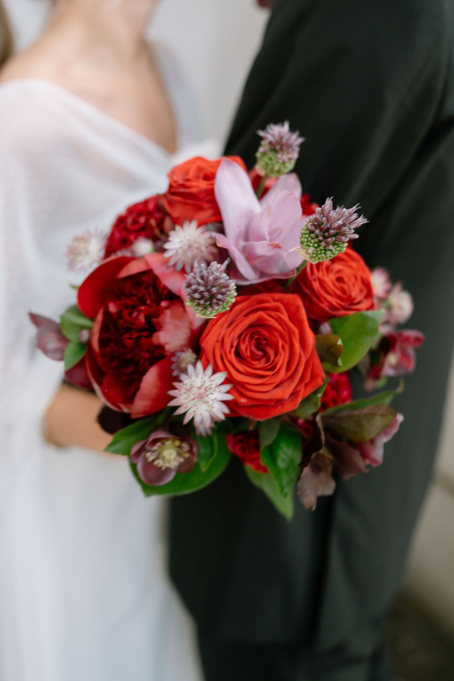Vibrant red and pink wedding bouquet with roses and mixed flowers.