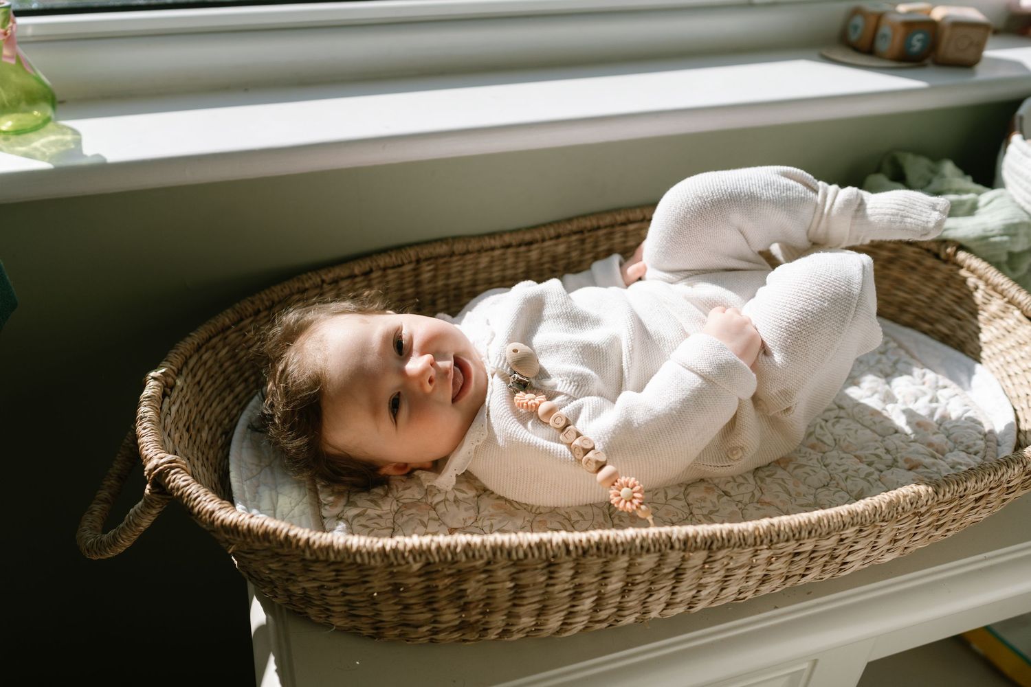 Sleeping baby resting peacefully in woven basket by window.