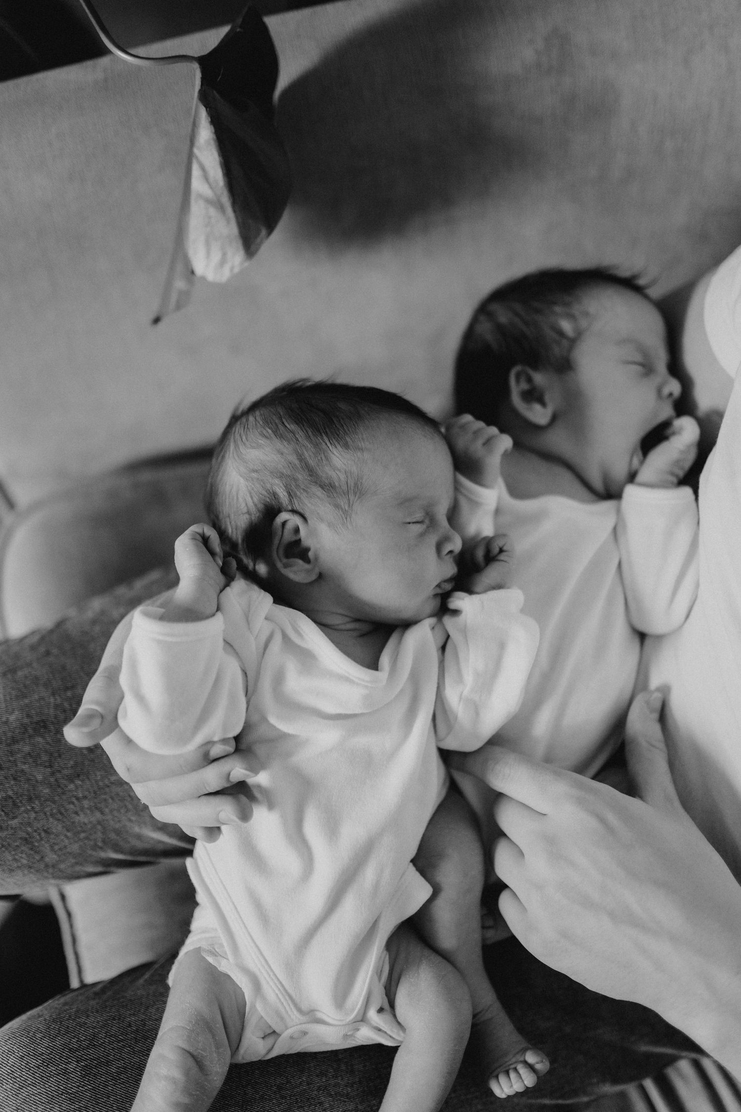 A newborn baby in white clothing sleeping peacefully on soft bedding.
