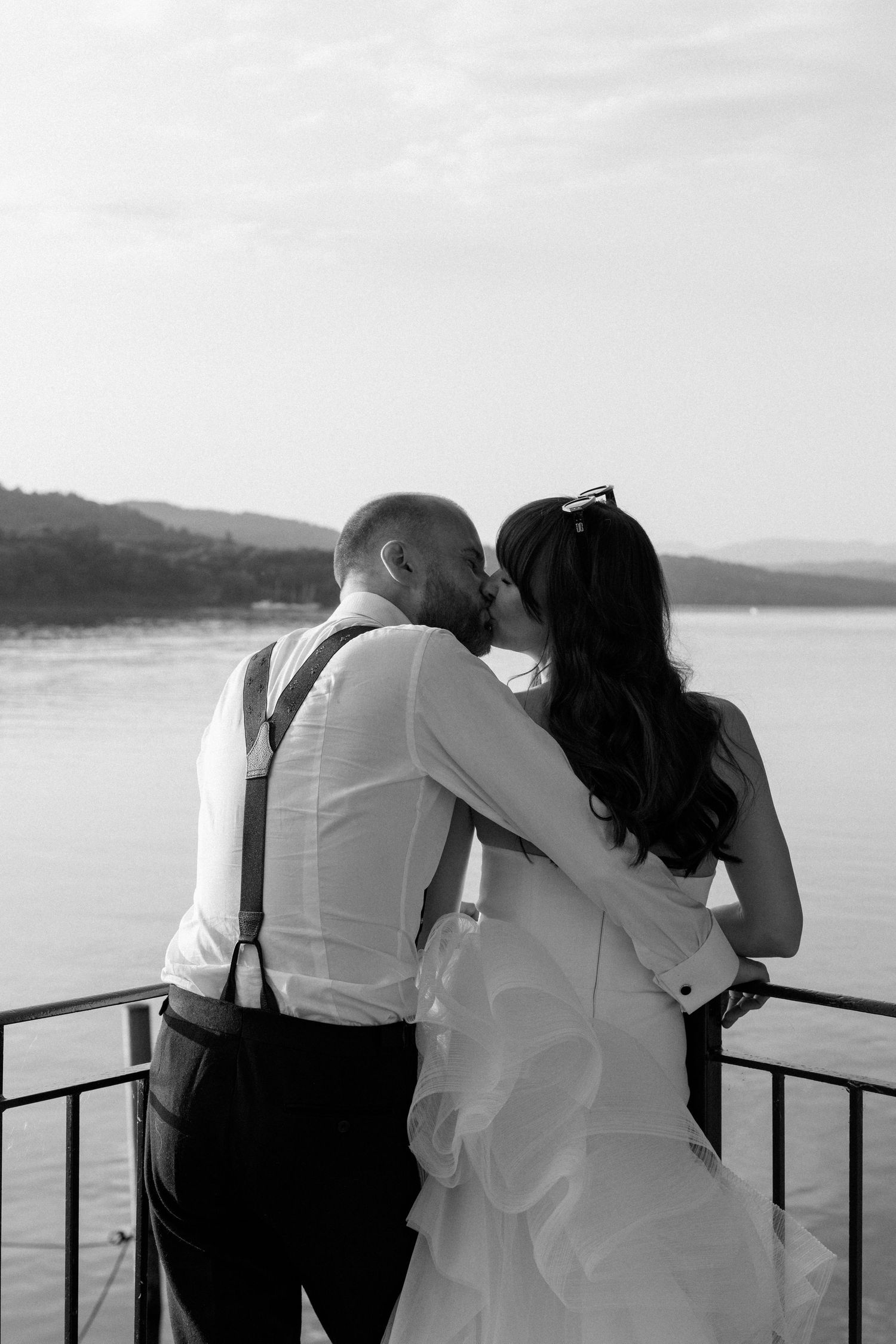 A tender black and white moment captured on a lakeside deck during sunset.