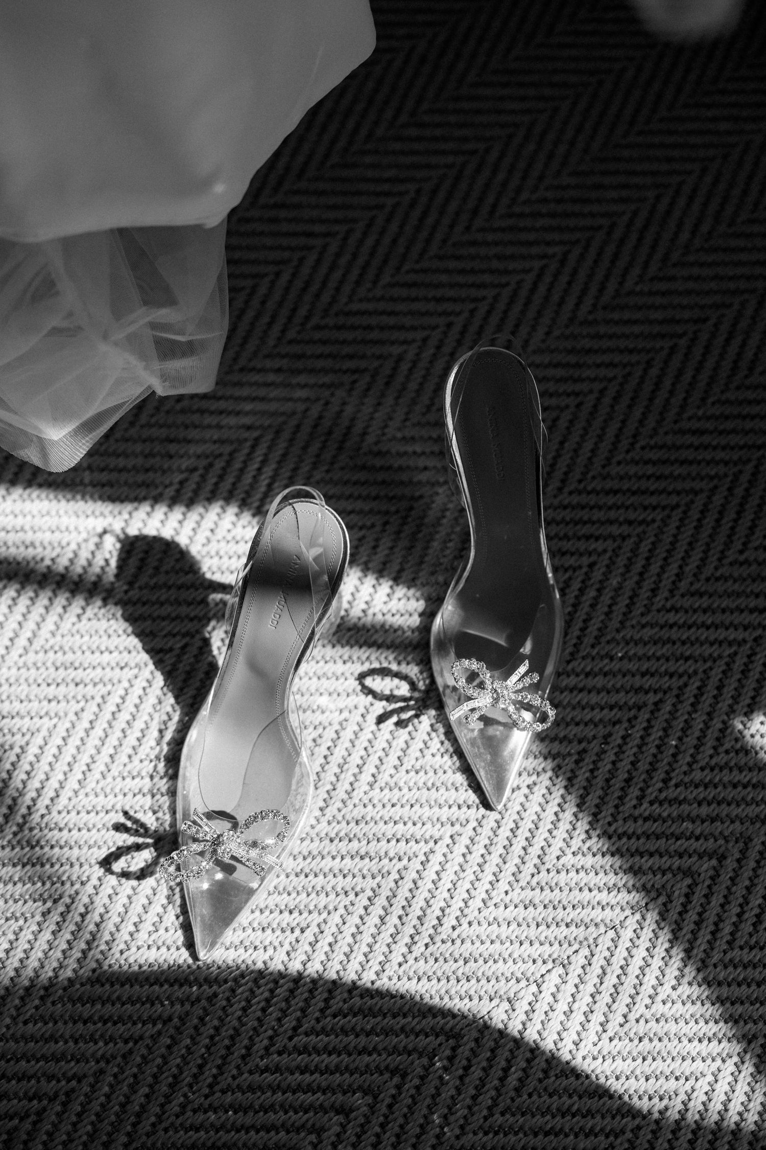 Elegant bridal shoes casting dramatic shadows on textured carpet.