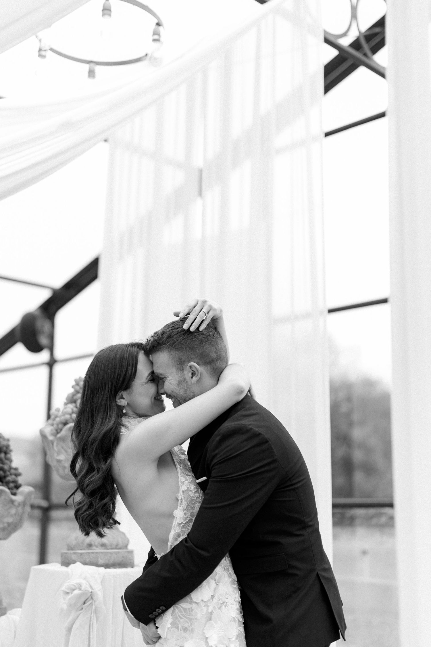 Romantic wedding dance moment under white draped ceiling with natural light.