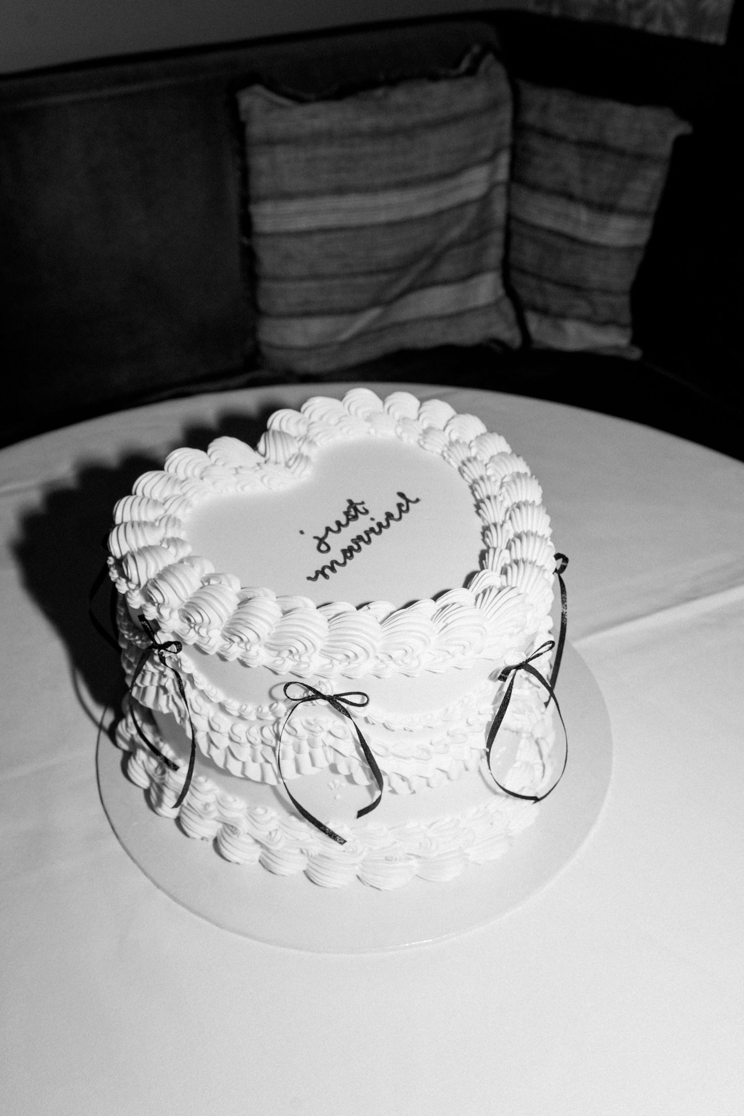 Black and white photo of heart-shaped wedding cake with delicate piped decorations.