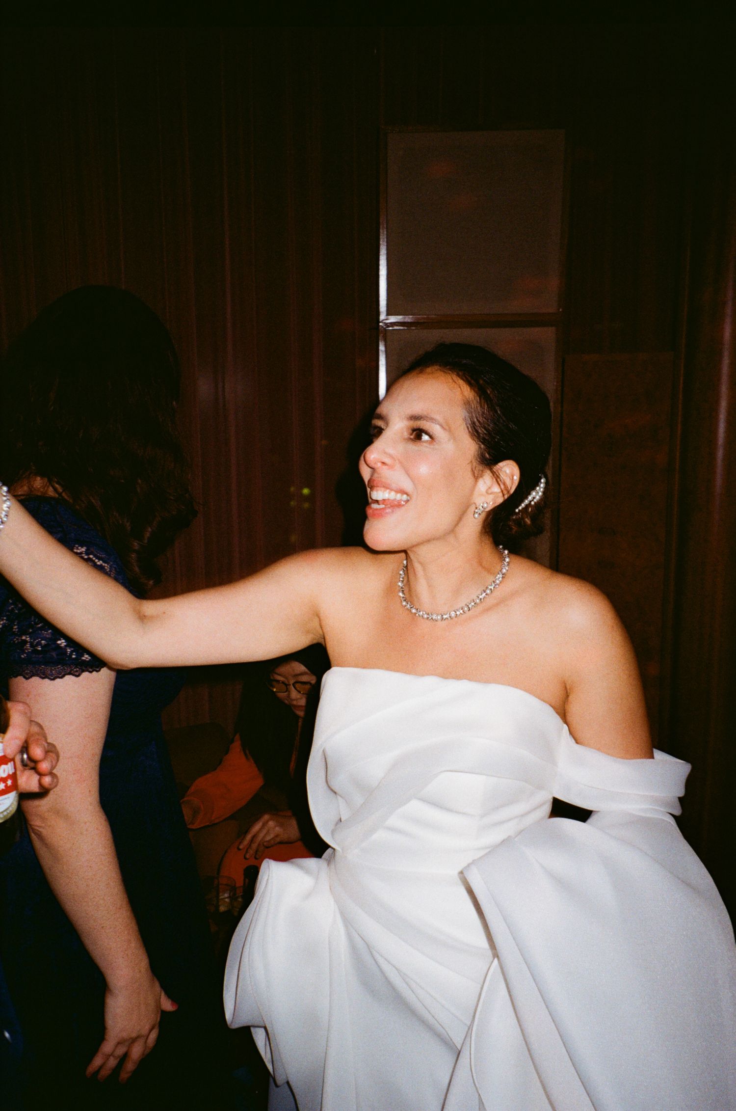 A bride in a structured white gown dances joyfully at her wedding reception.
