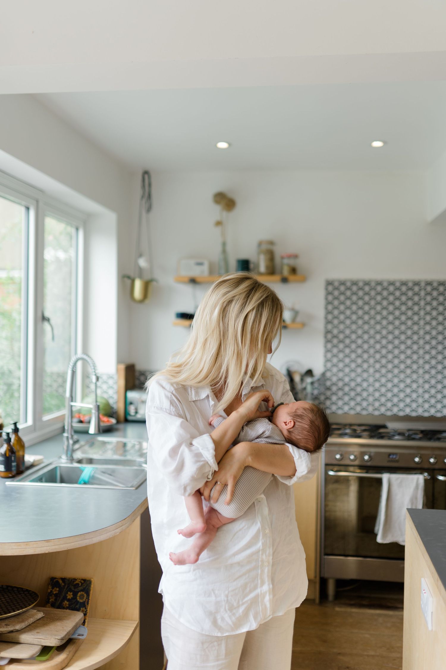A series of candid moments in a bright modern kitchen showing tender embraces between parent and child.