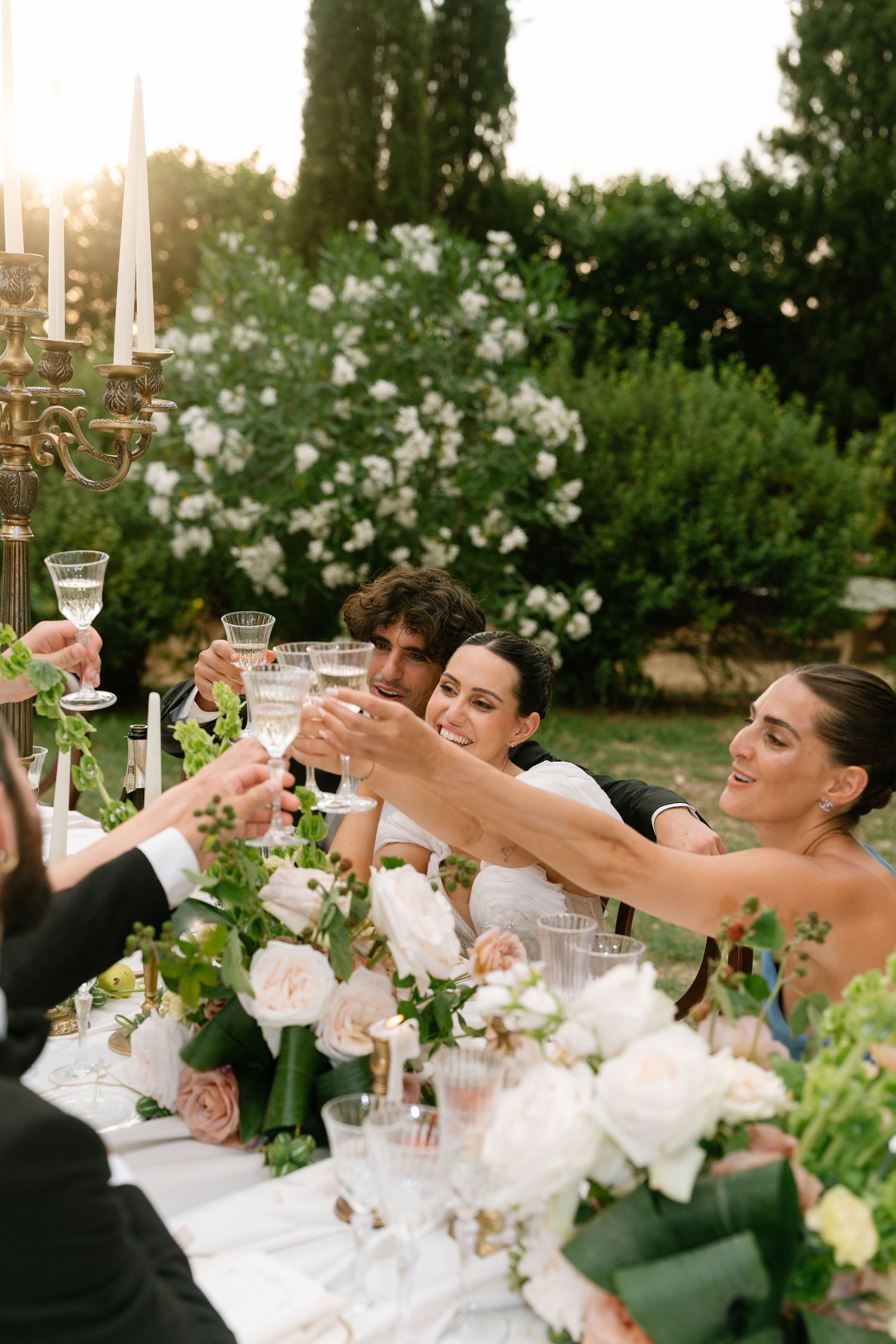 Wedding guests raising glasses in a toast at an elegant outdoor garden reception.