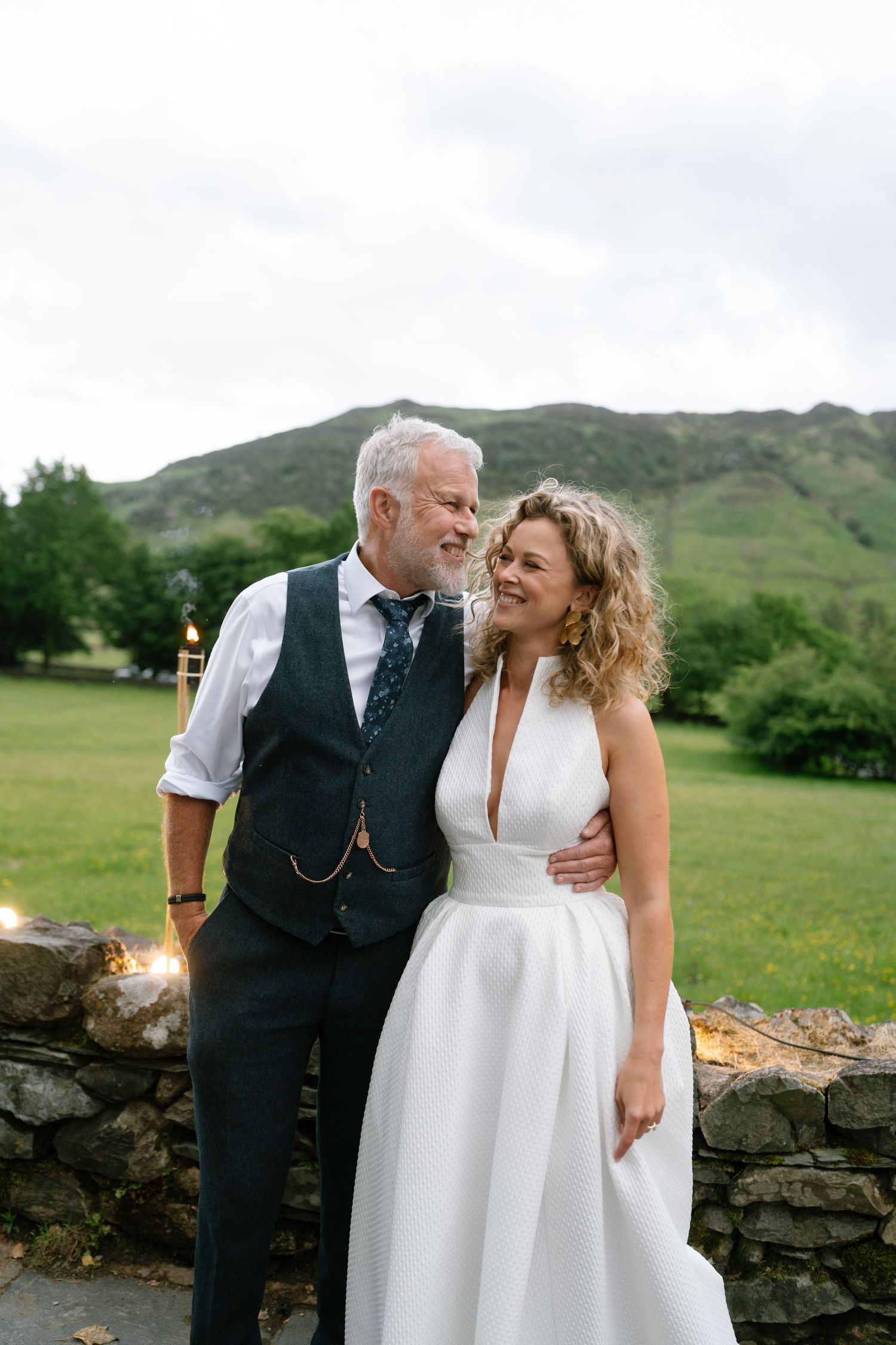 Romantic outdoor wedding portrait with scenic mountain landscape in background.