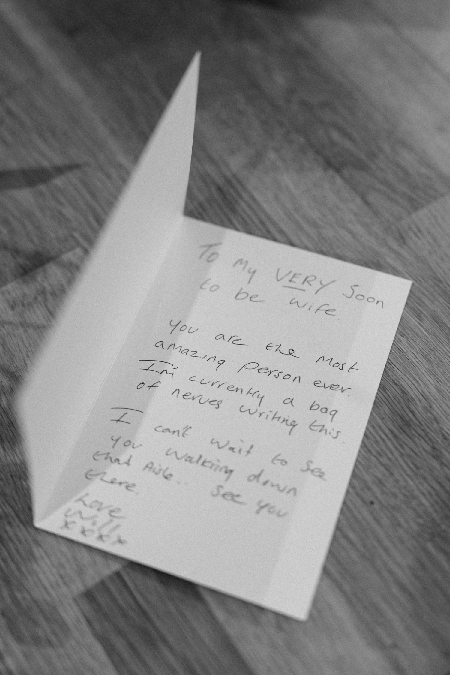 Handwritten love note on white paper placed on wooden table surface.