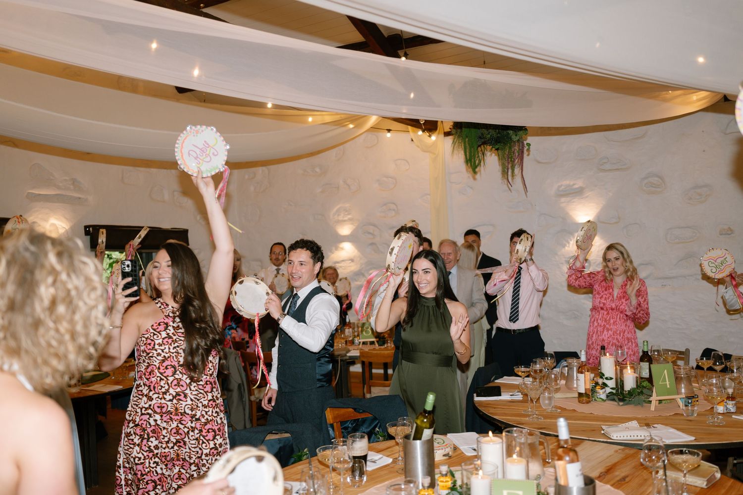 Wedding reception celebration with guests dancing and socializing in a warmly lit banquet hall.