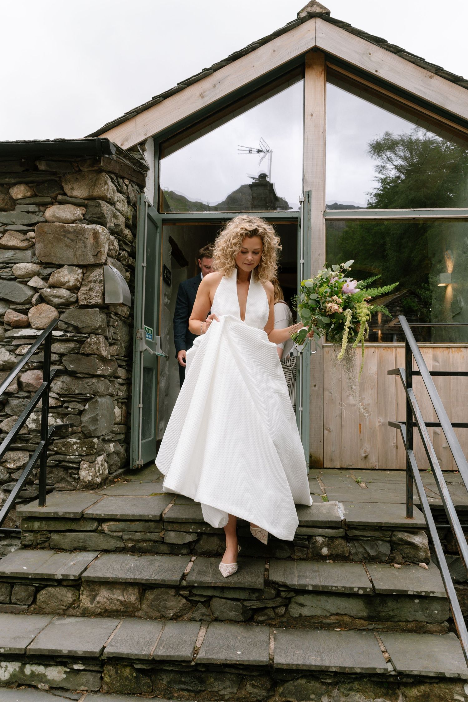 Sequential shots of a bride's dress trailing along a rustic stone pathway outside a building.