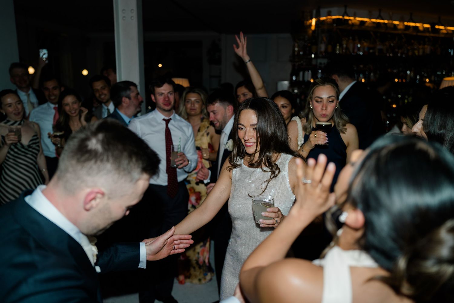 Energetic wedding reception dance floor with bride in white dress celebrating with guests.