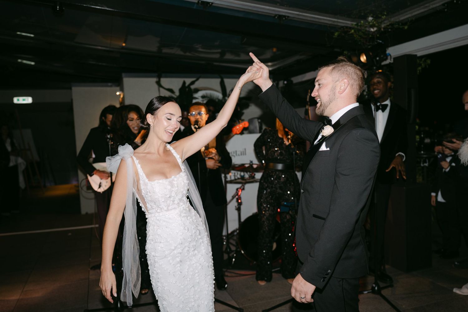 Wedding guests dance and celebrate on a dimly lit dance floor during the reception.