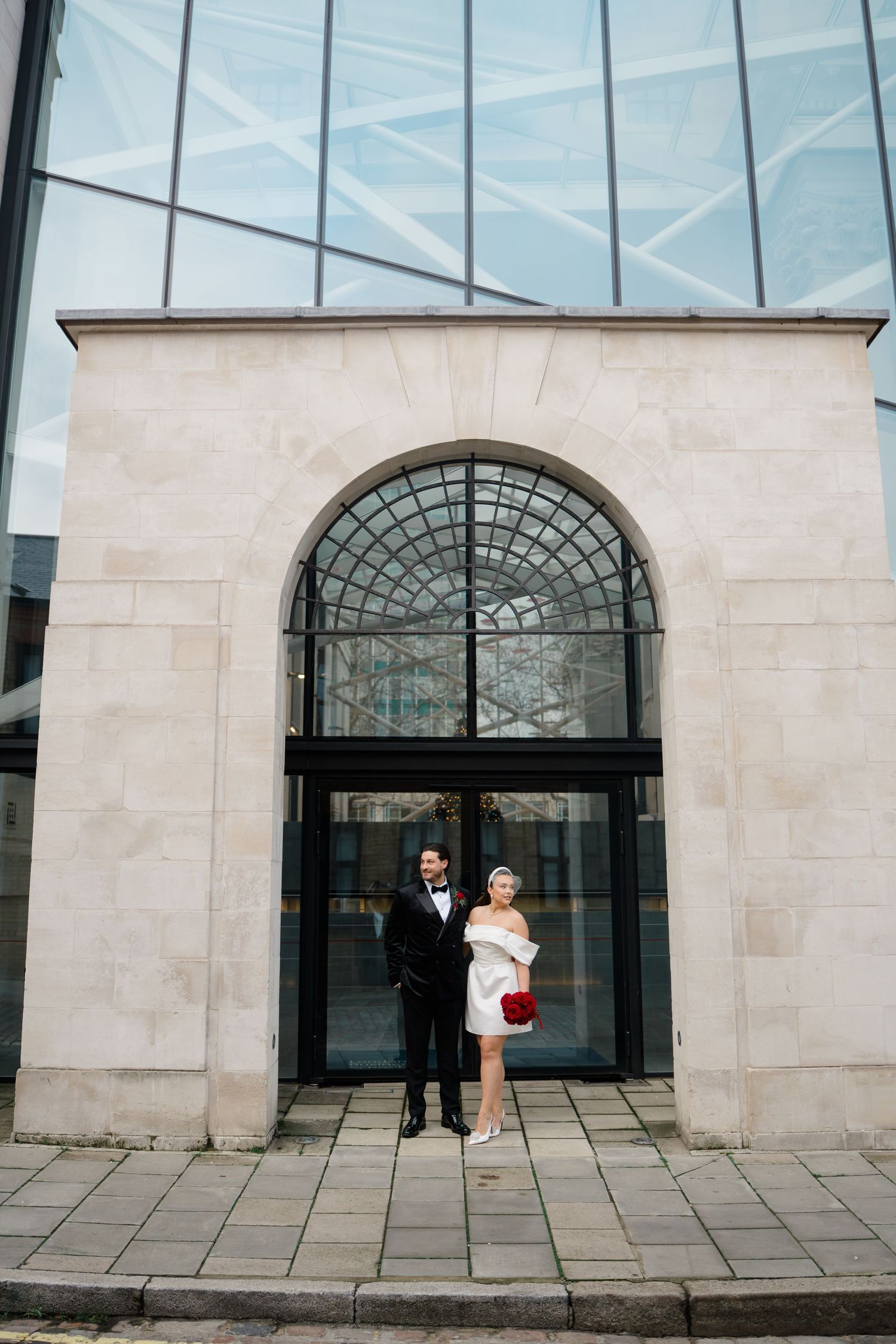 Modern wedding portraits with couple against glass and stone archways.