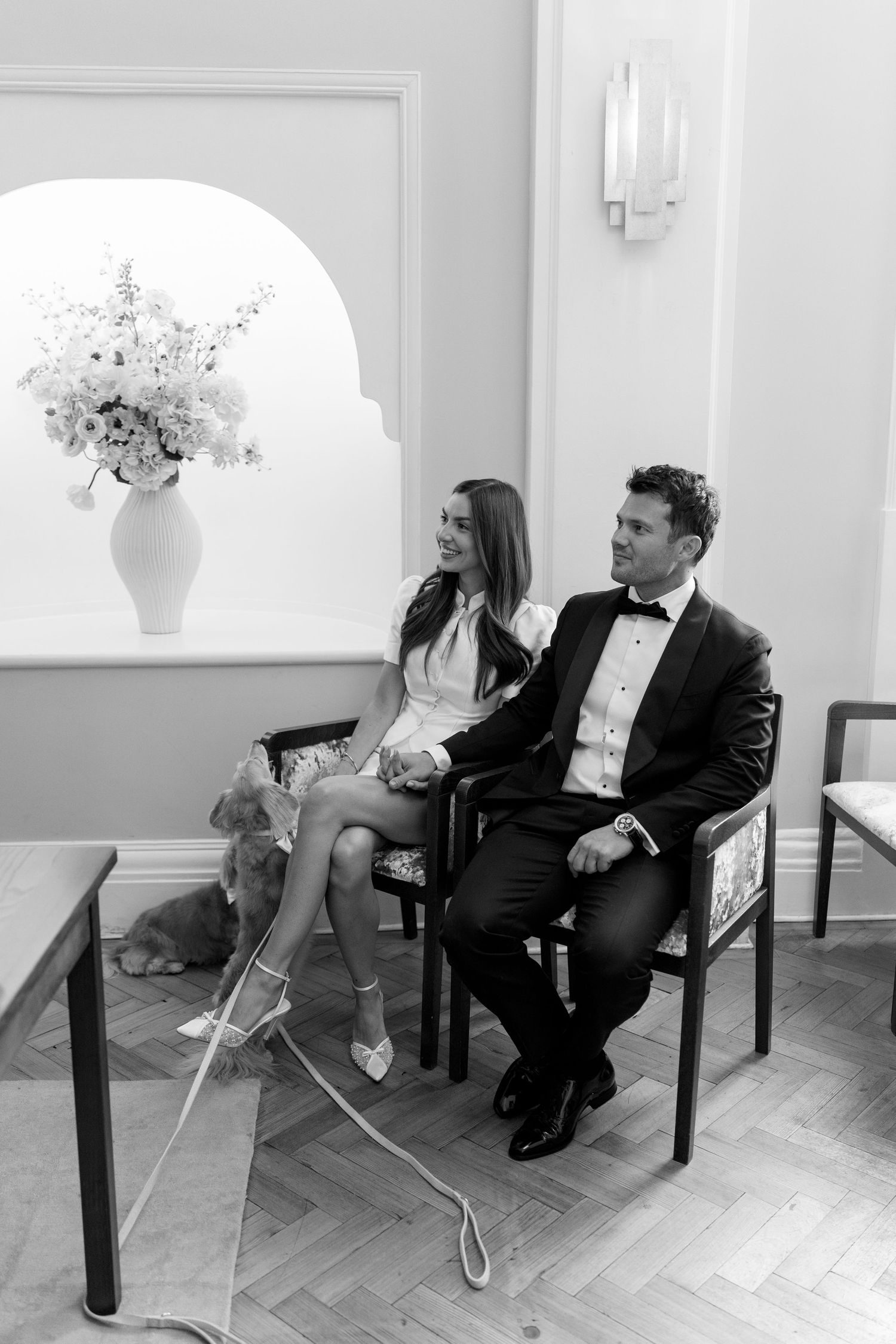 Newlyweds seated with their dog at a civil wedding ceremony.