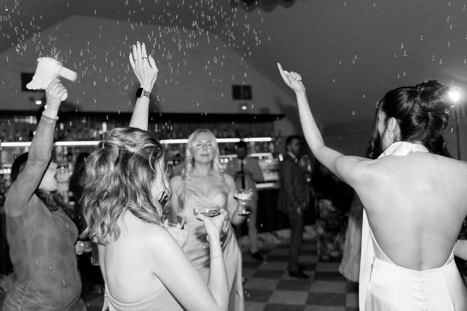 Black and white photo of bride and guests dancing and celebrating on the wedding dance floor.