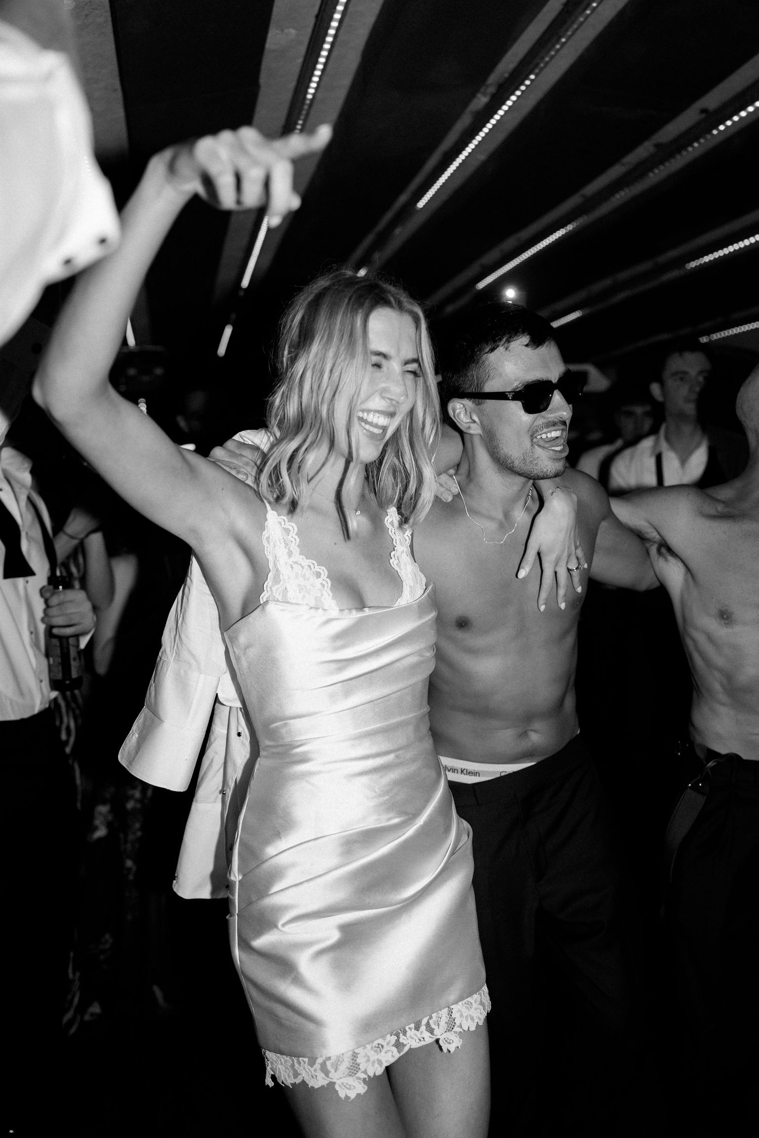 Black and white photo of bride in silk slip dress dancing joyfully at wedding after-party.
