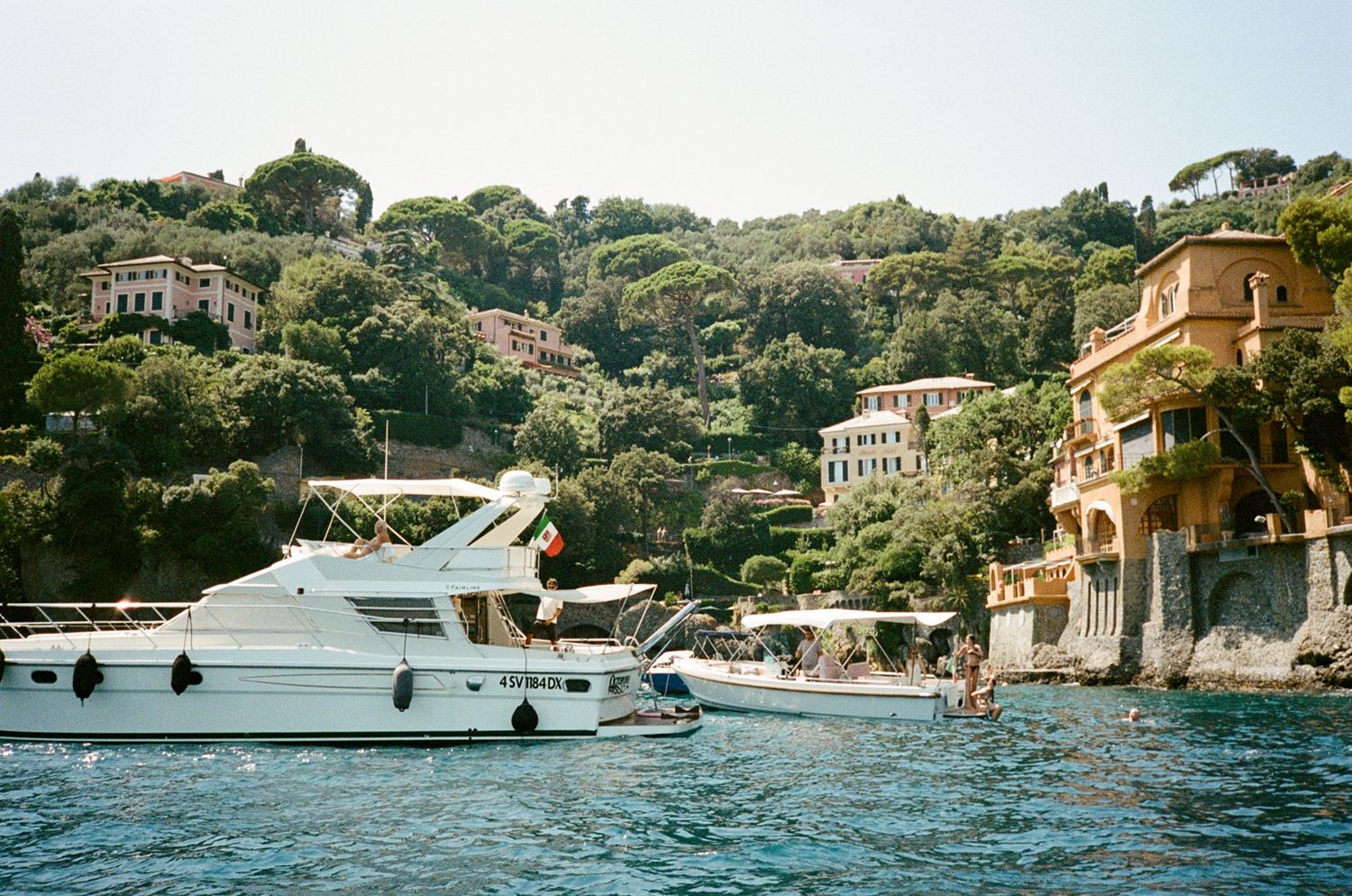 White luxury yacht moored near colorful hillside villas along the scenic Portofino Italian coastline.