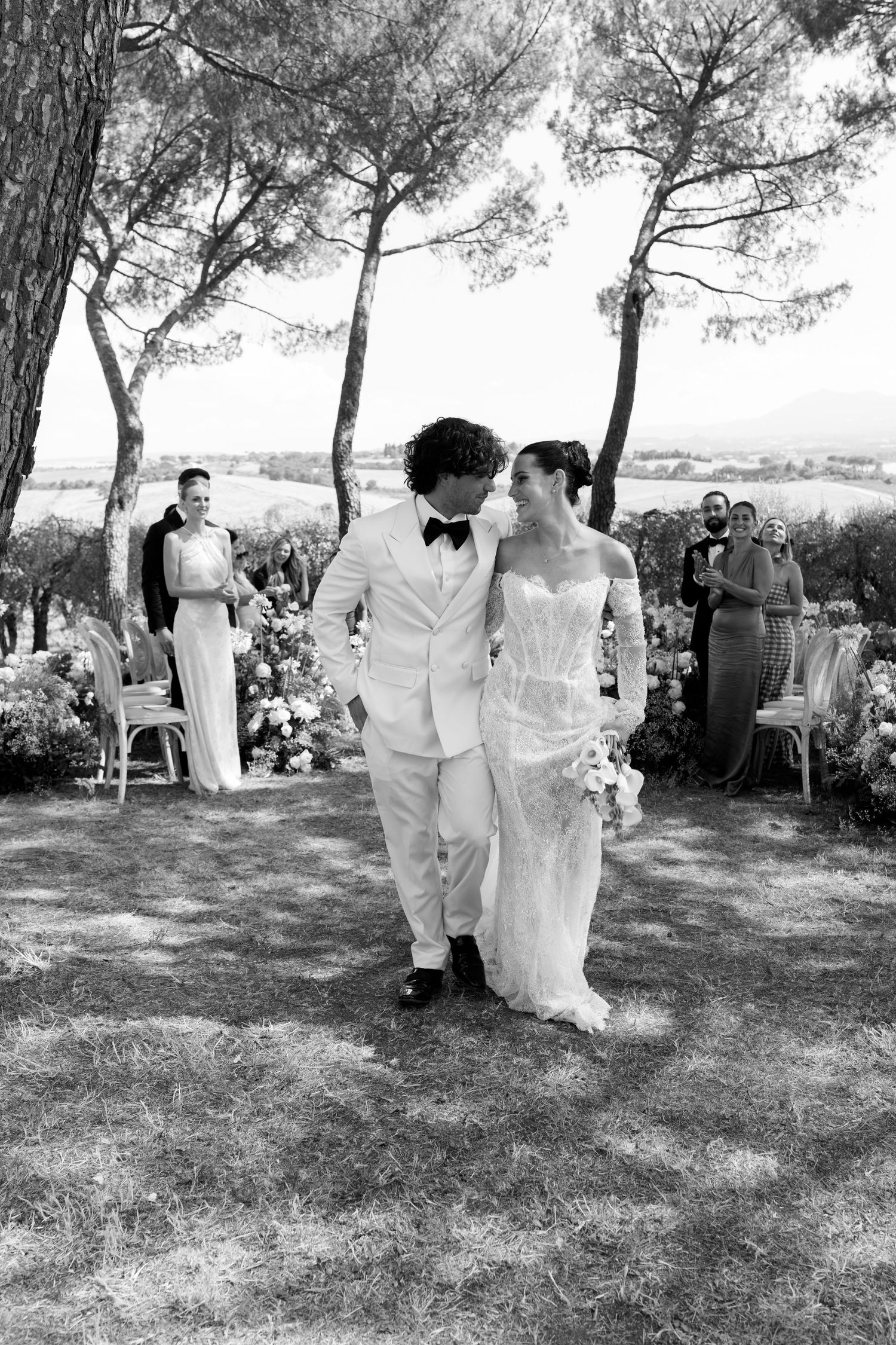 Black and white photos capturing moments from an outdoor wedding ceremony under pine trees.