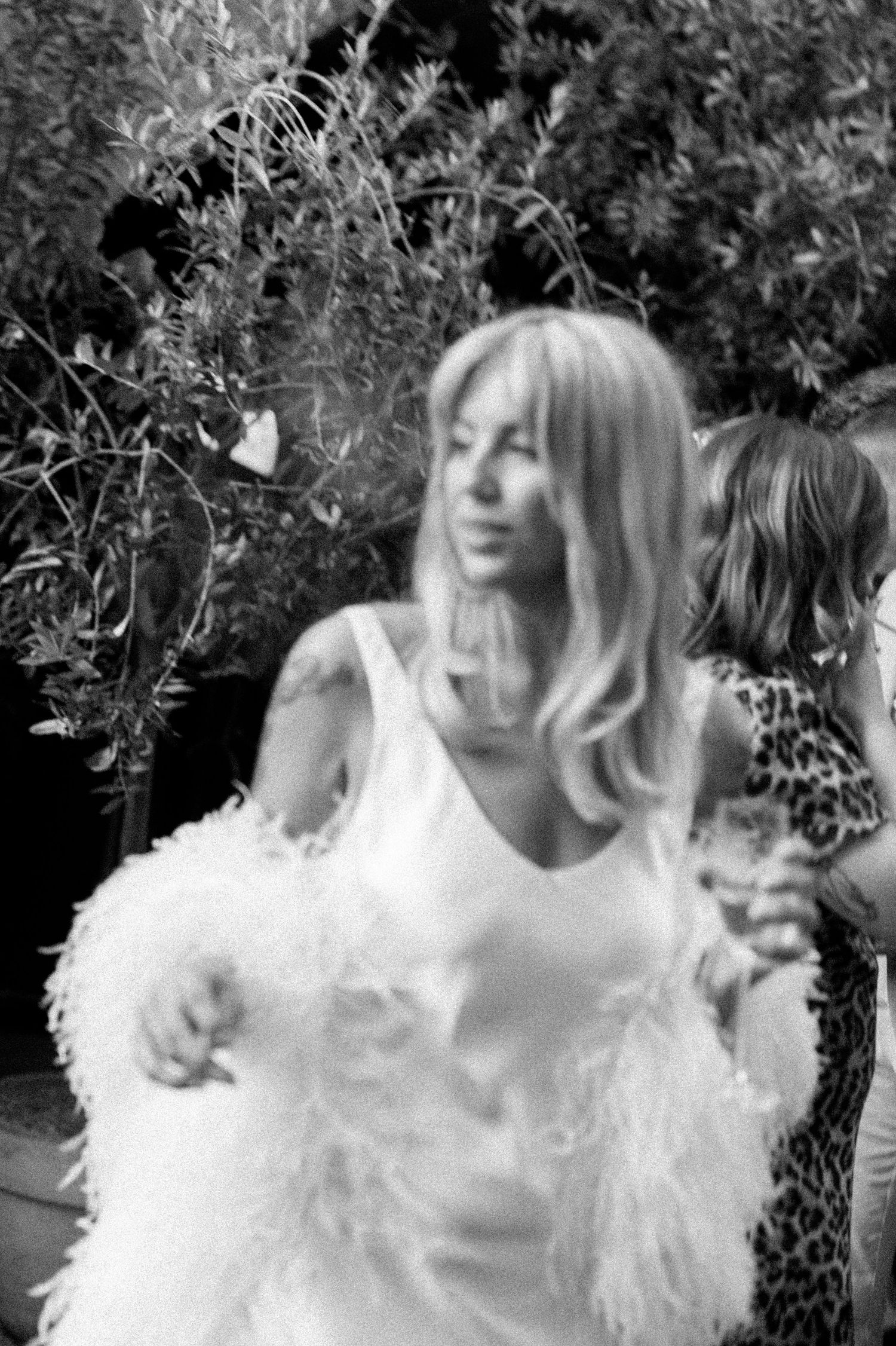 A series of black and white photos showing someone in a white feathered outfit dancing and moving.