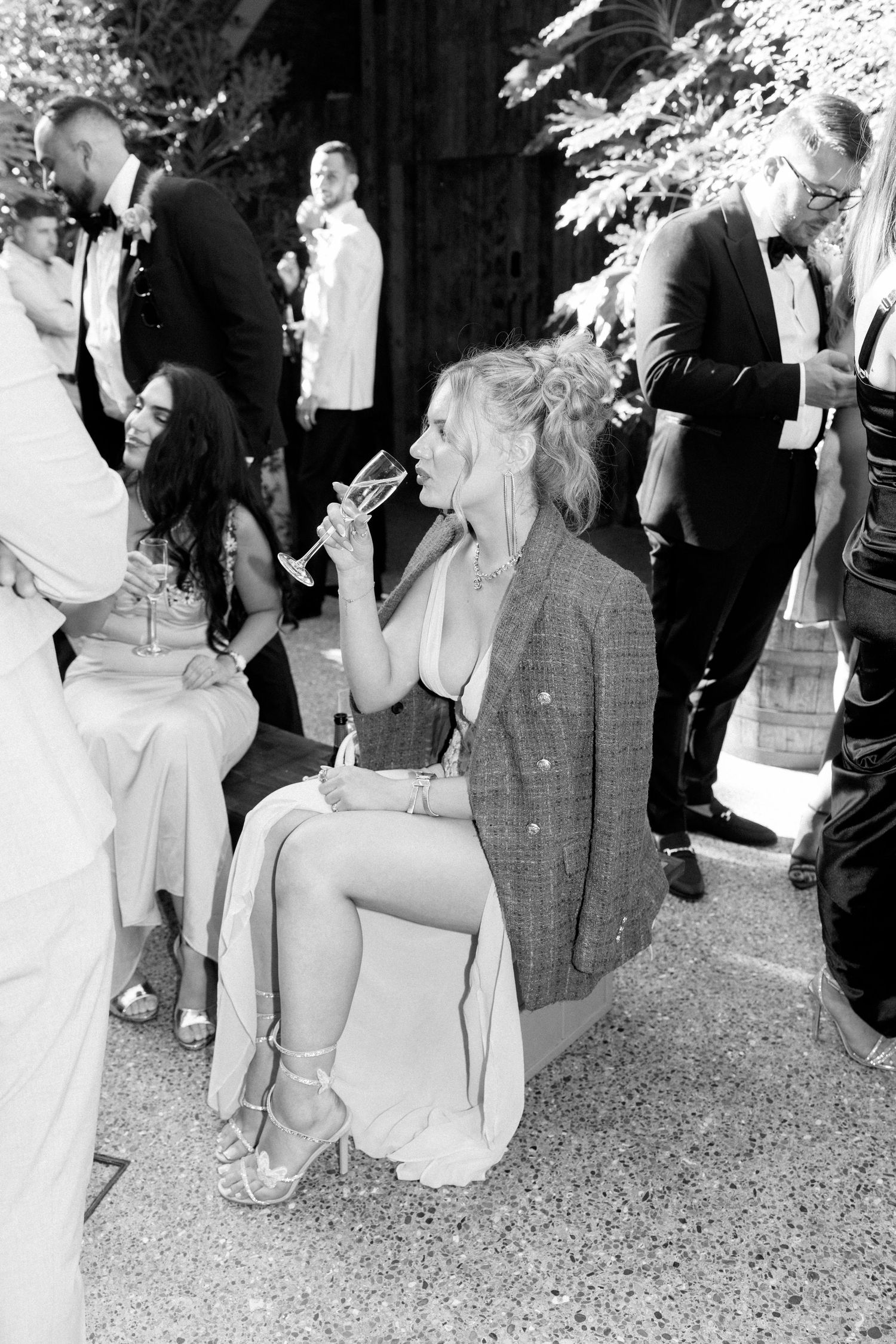 Black and white photo of guests enjoying drinks at outdoor wedding reception.