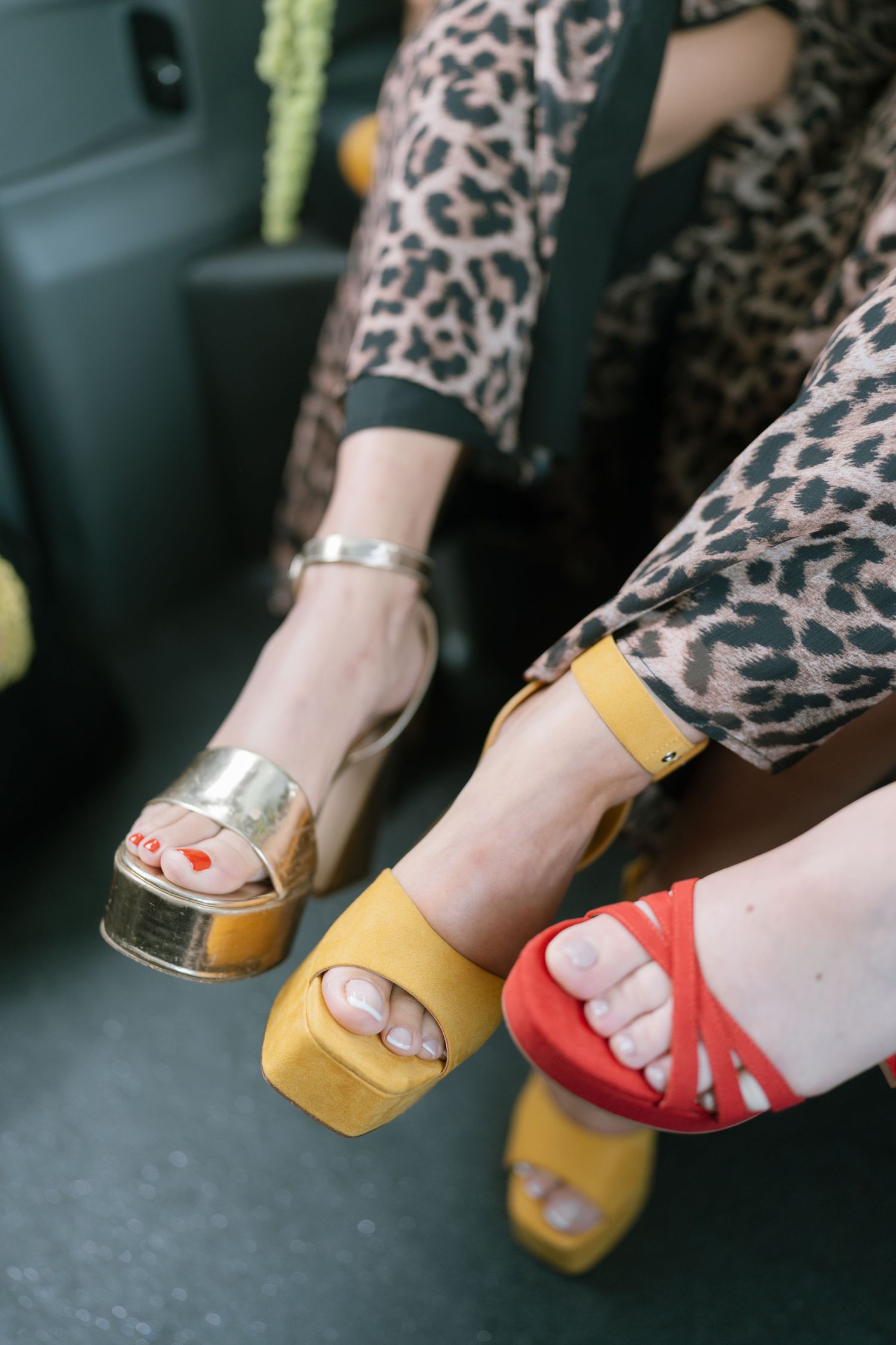 Close-up of feet wearing leopard print and colorful sandals in yellow and red.
