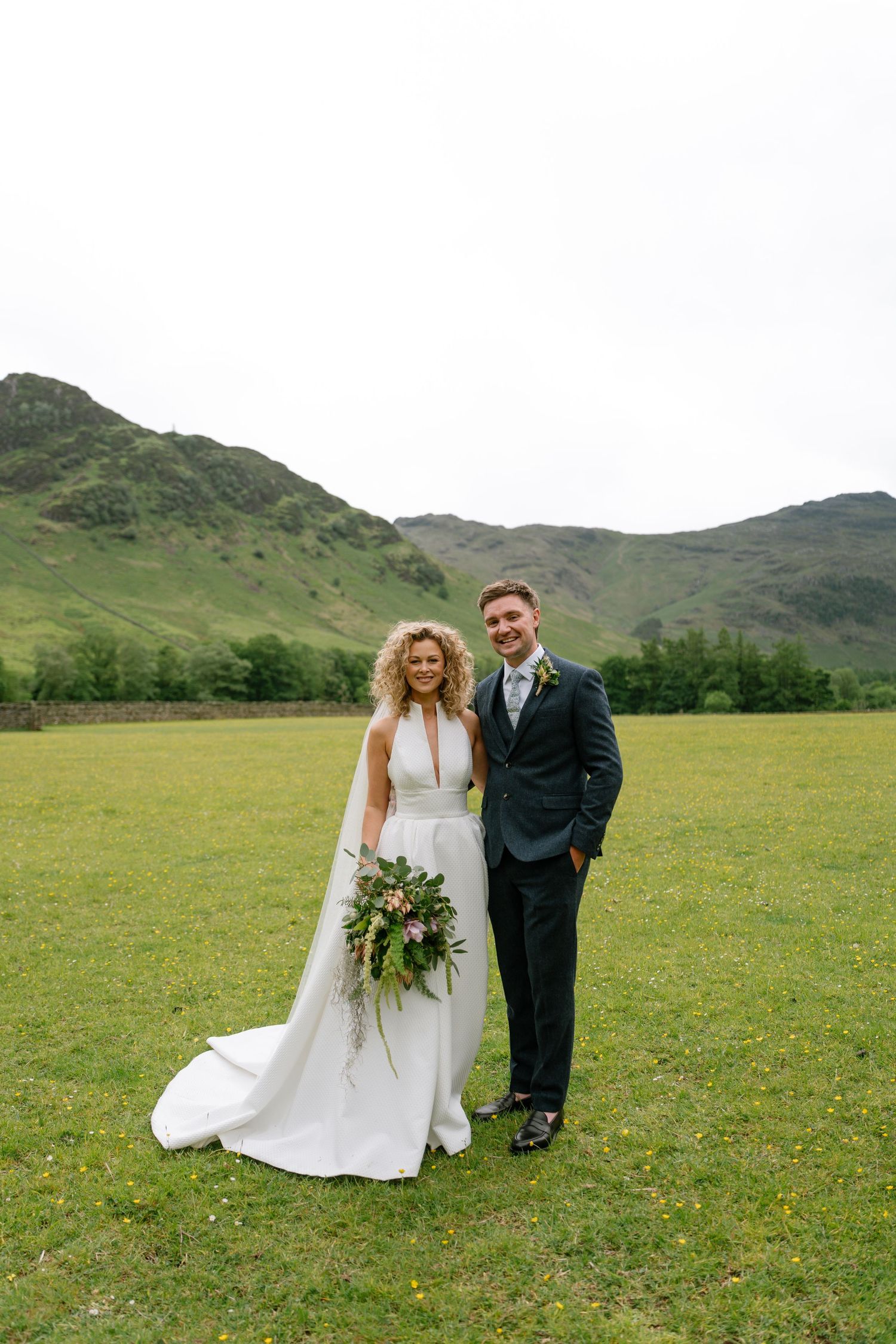 Wedding couple poses for portraits in scenic mountain meadow setting.