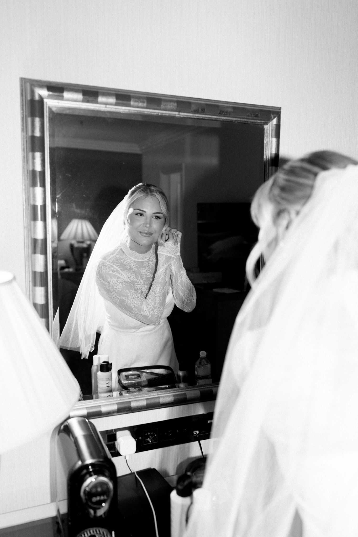 Multiple reflections of a bride in white veil looking at herself in a mirror.
