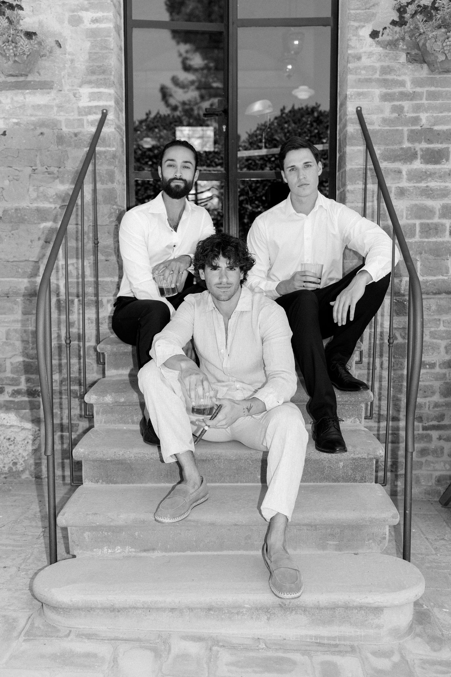 Black and white photos of people in white outfits posing casually on brick building steps.