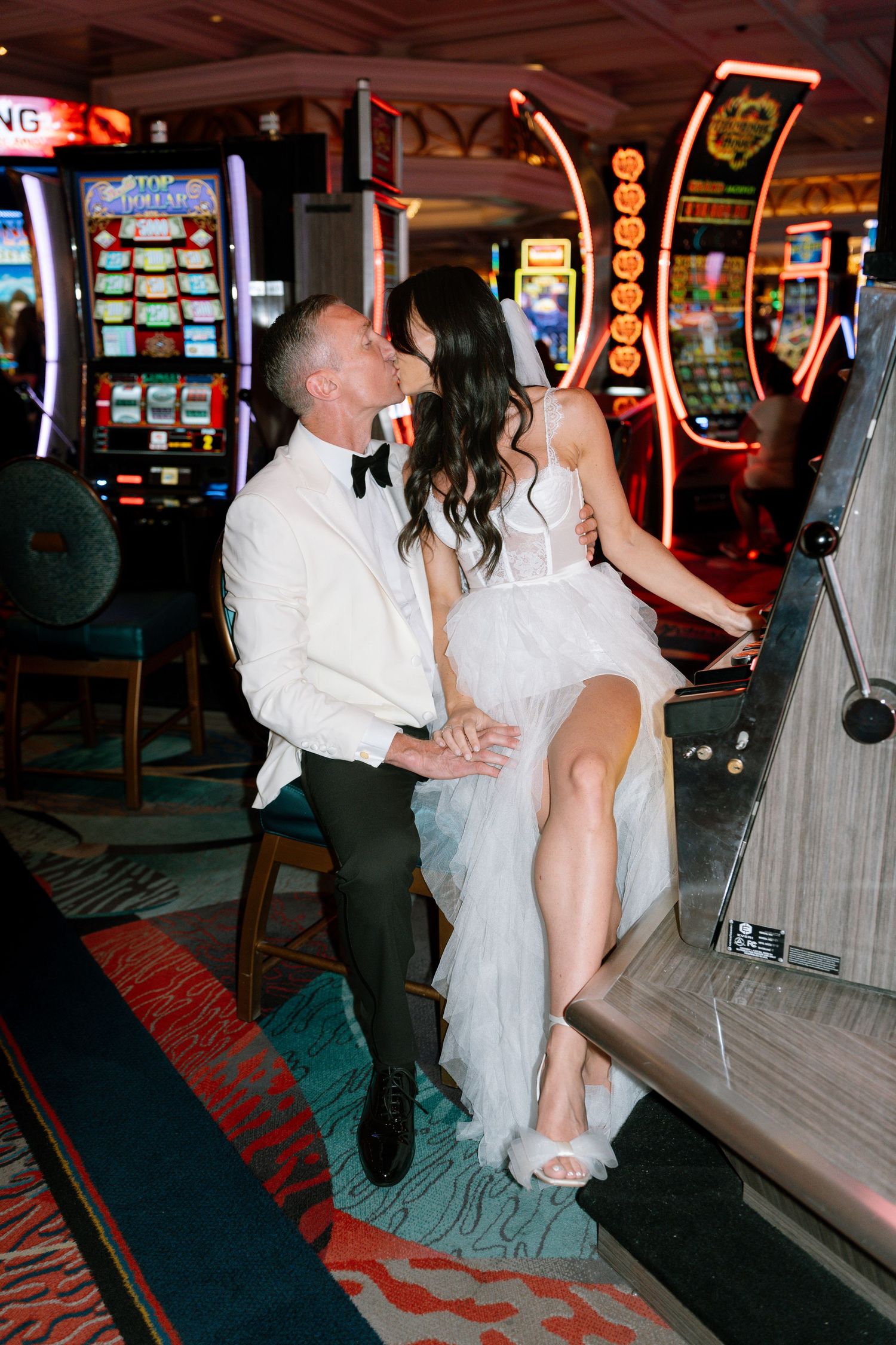 Wedding couple shares candid moments between casino slot machines.