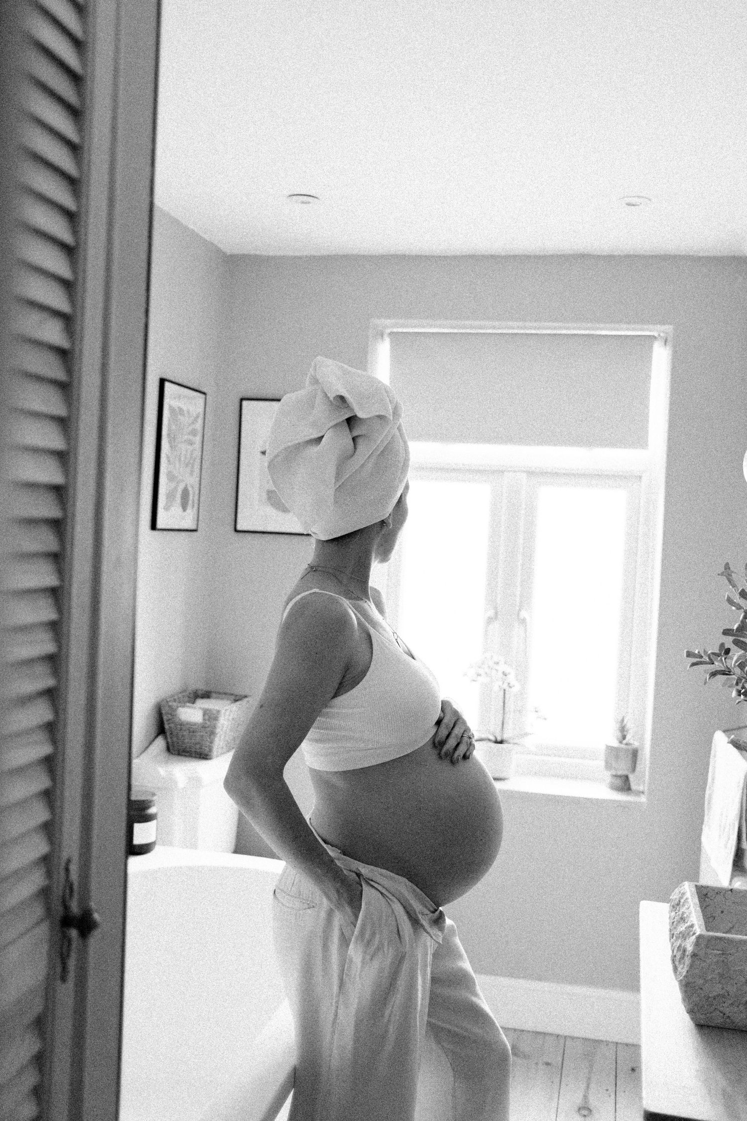Progressive shots of a pregnant woman in white dress against a bright interior wall.