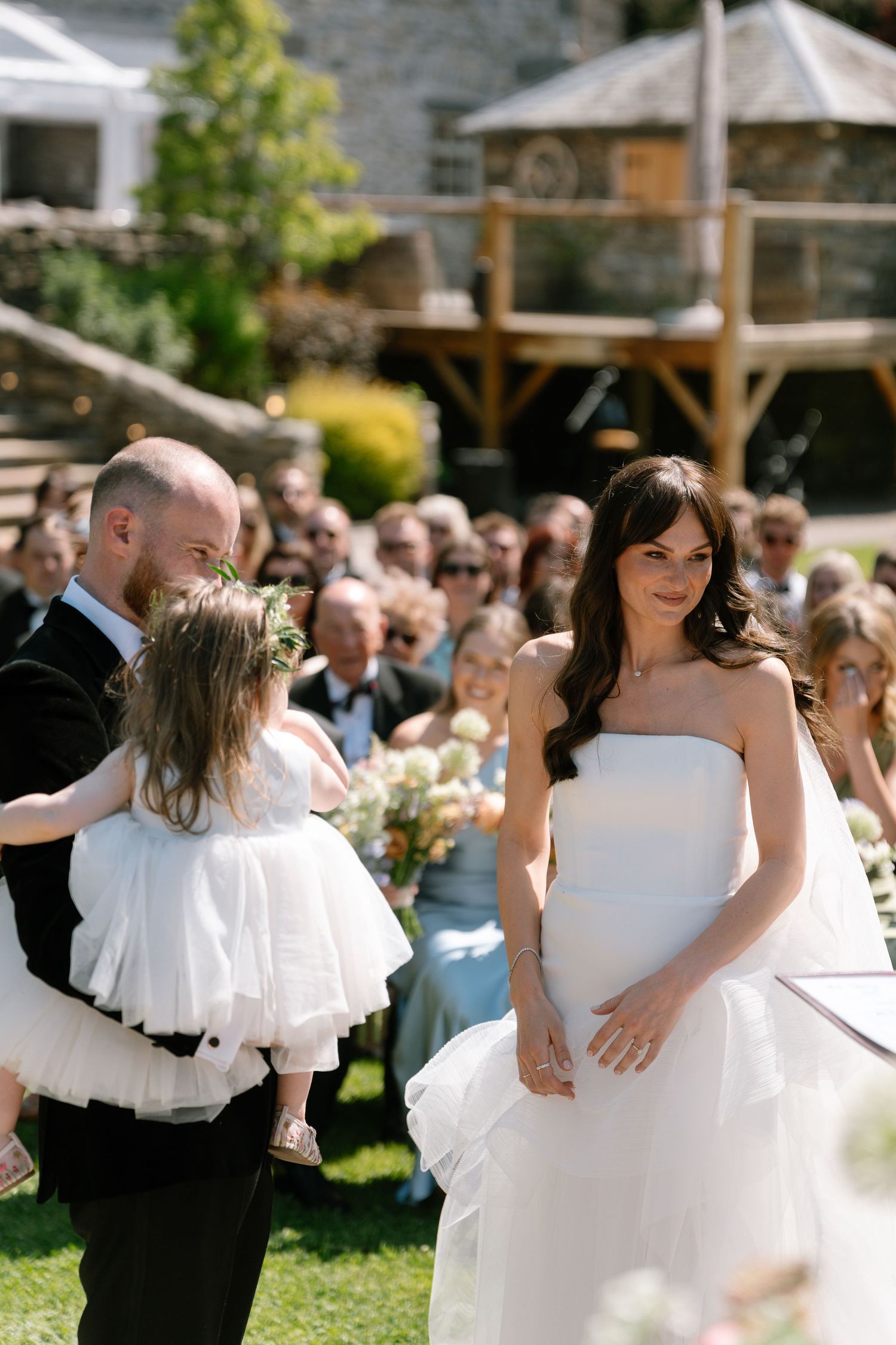Couples dance together at sunny outdoor wedding reception with garden backdrop.