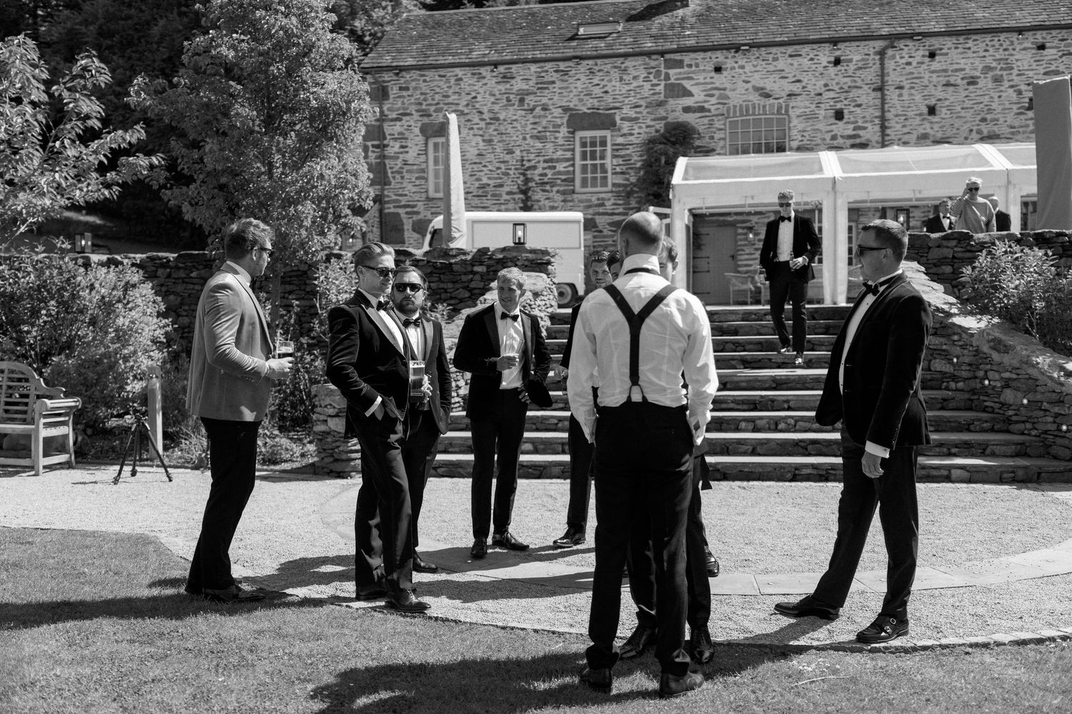 Wedding party members gathered outside historic stone building.