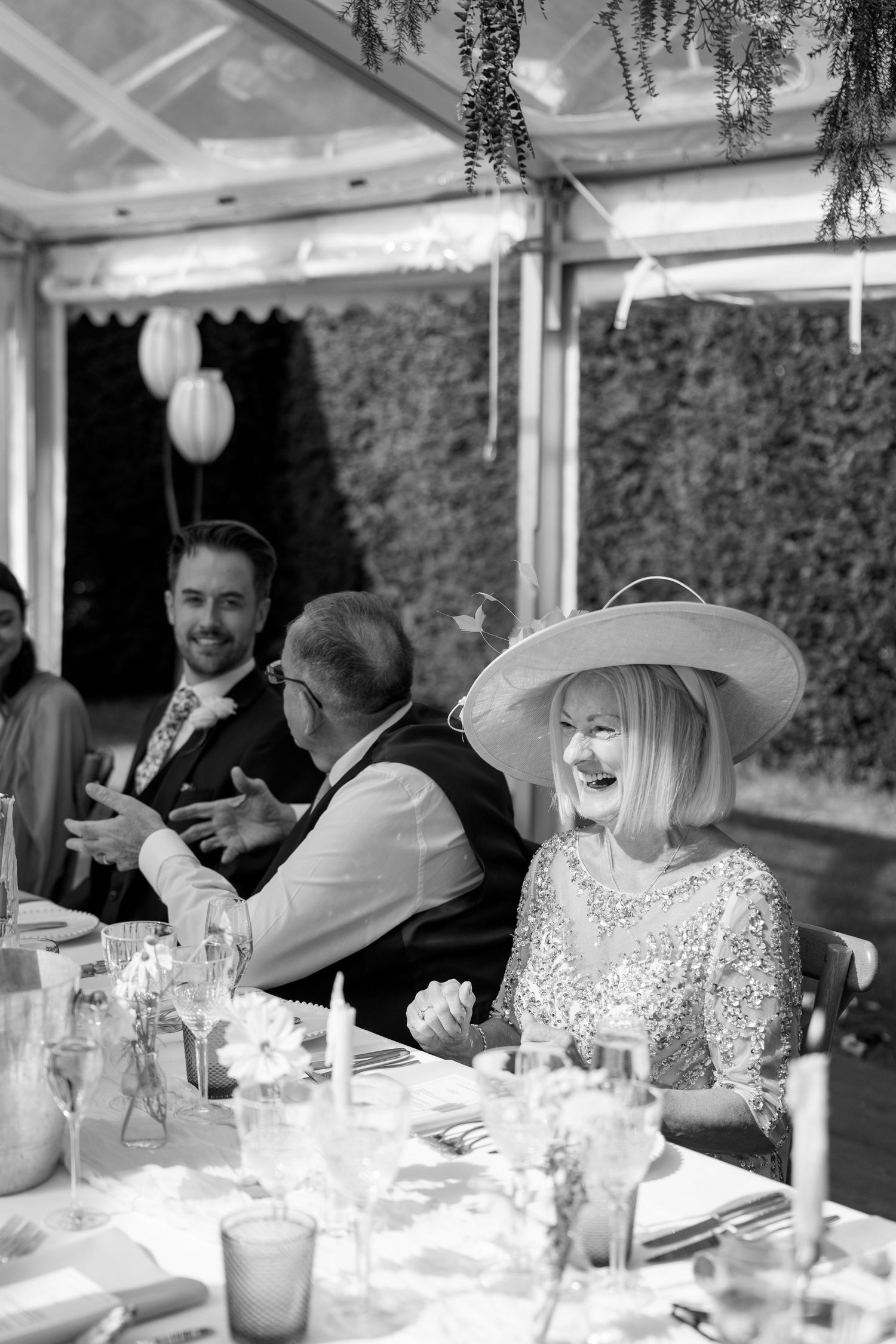 Wedding guests enjoying conversation at an elegant outdoor reception under hanging lanterns.