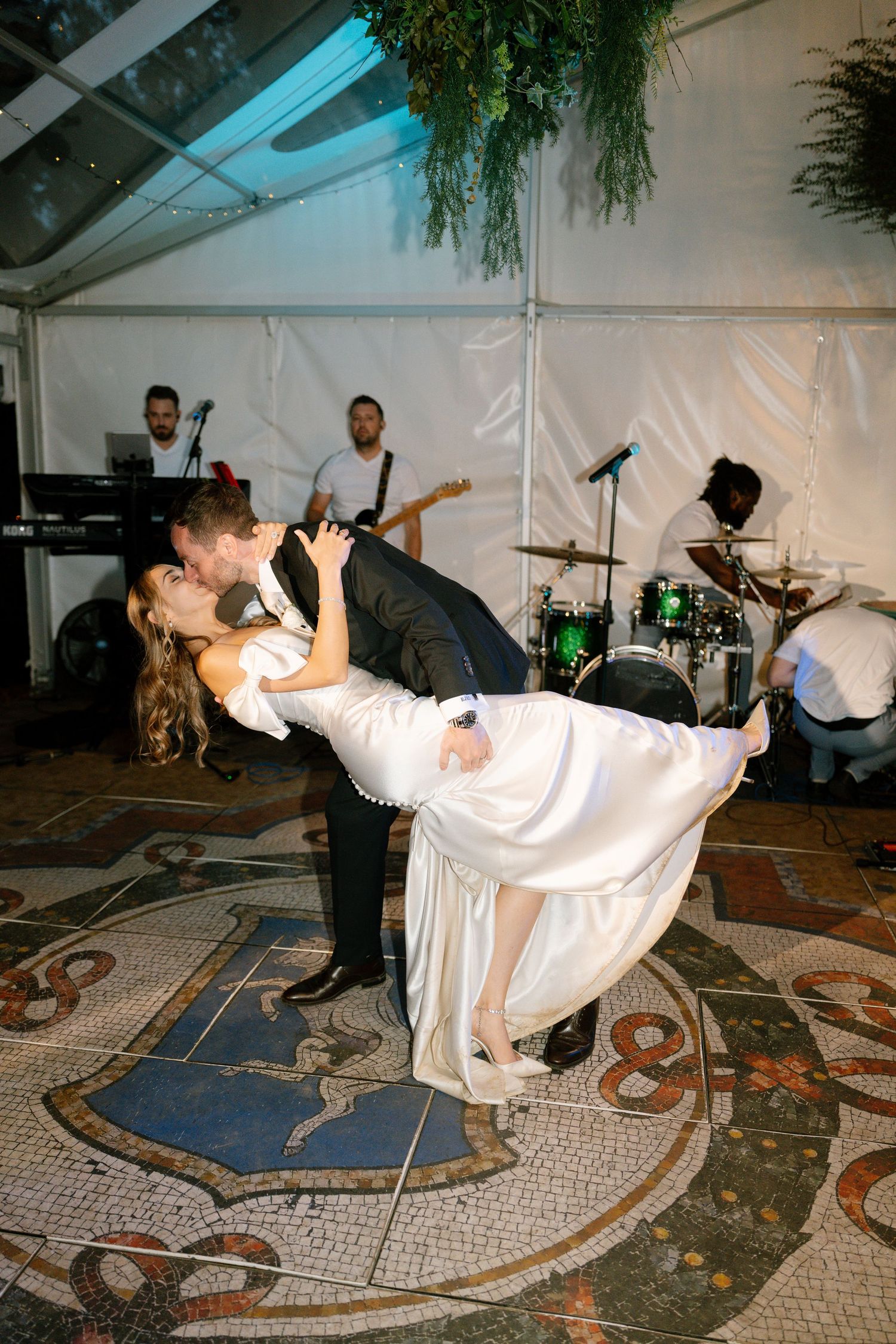 A romantic dip during a wedding dance with the live band visible in the background.