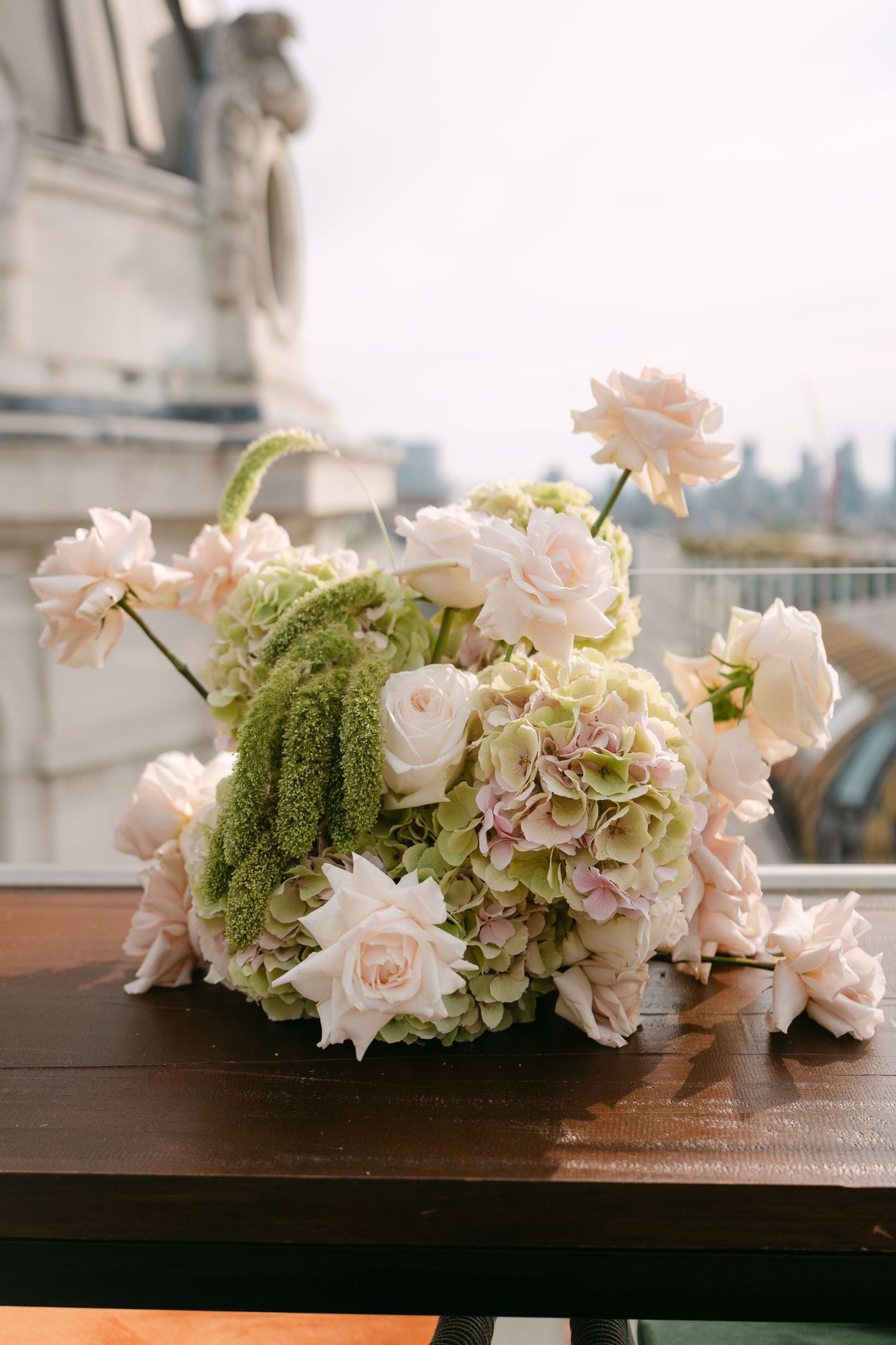 Elegant floral arrangement with pink roses and green accents on a wooden surface.