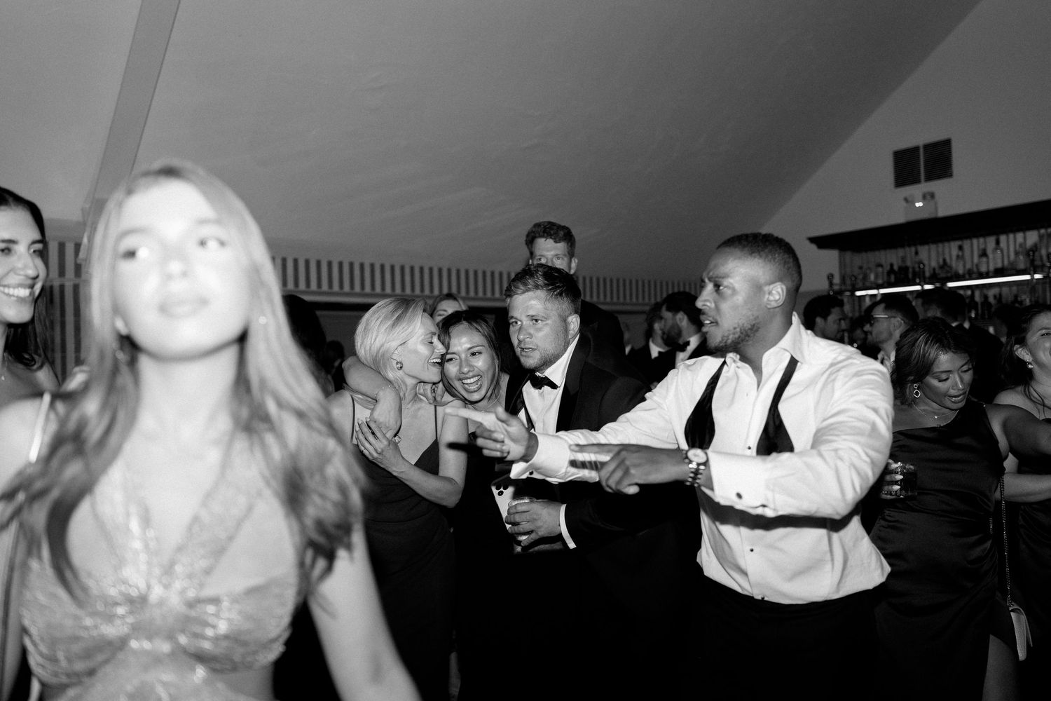 Wedding guests dance and celebrate together on the dance floor in black and white photo.