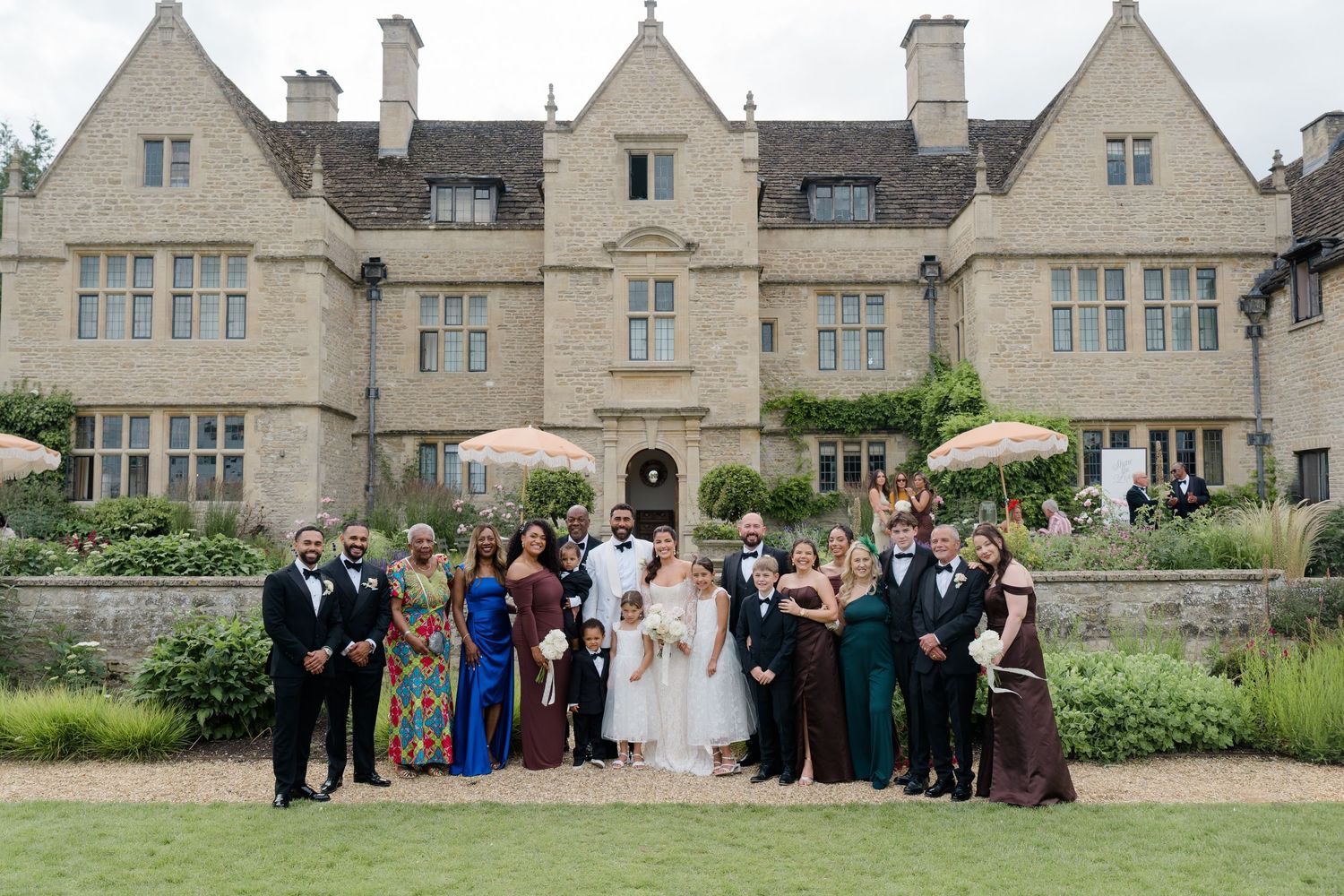 Wedding party group photo in front of an elegant stone manor house venue.