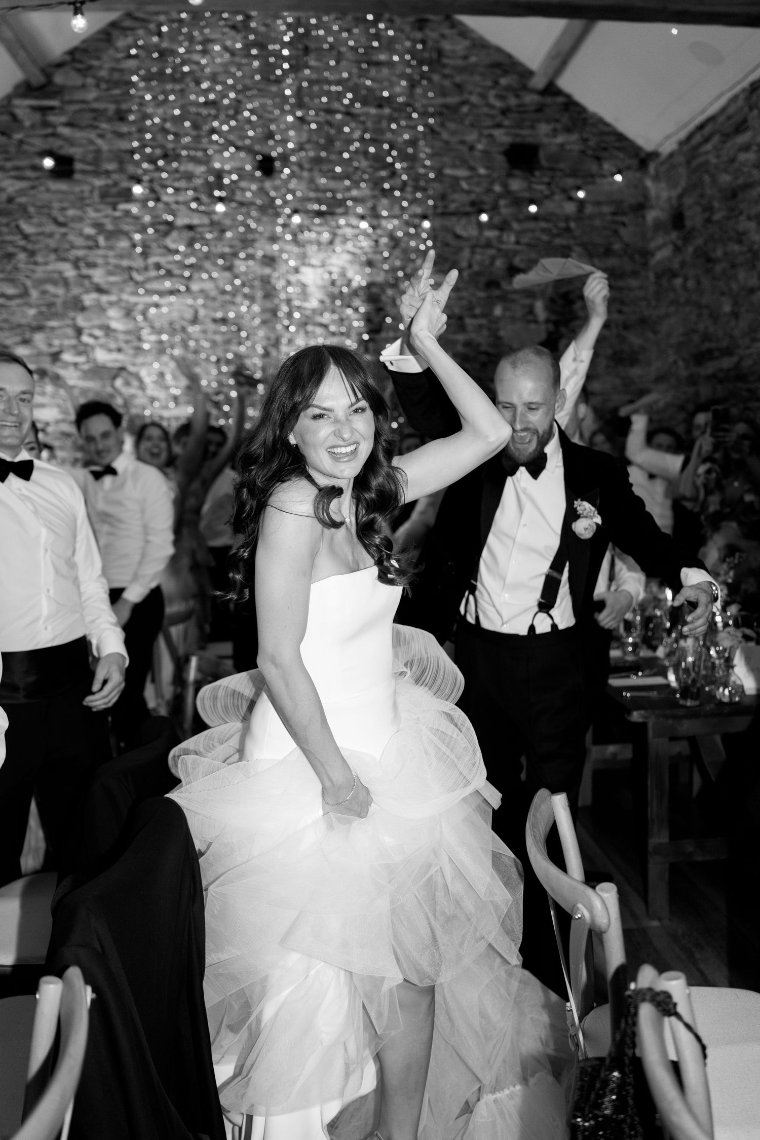 Wedding reception dance party with string lights in rustic stone venue.