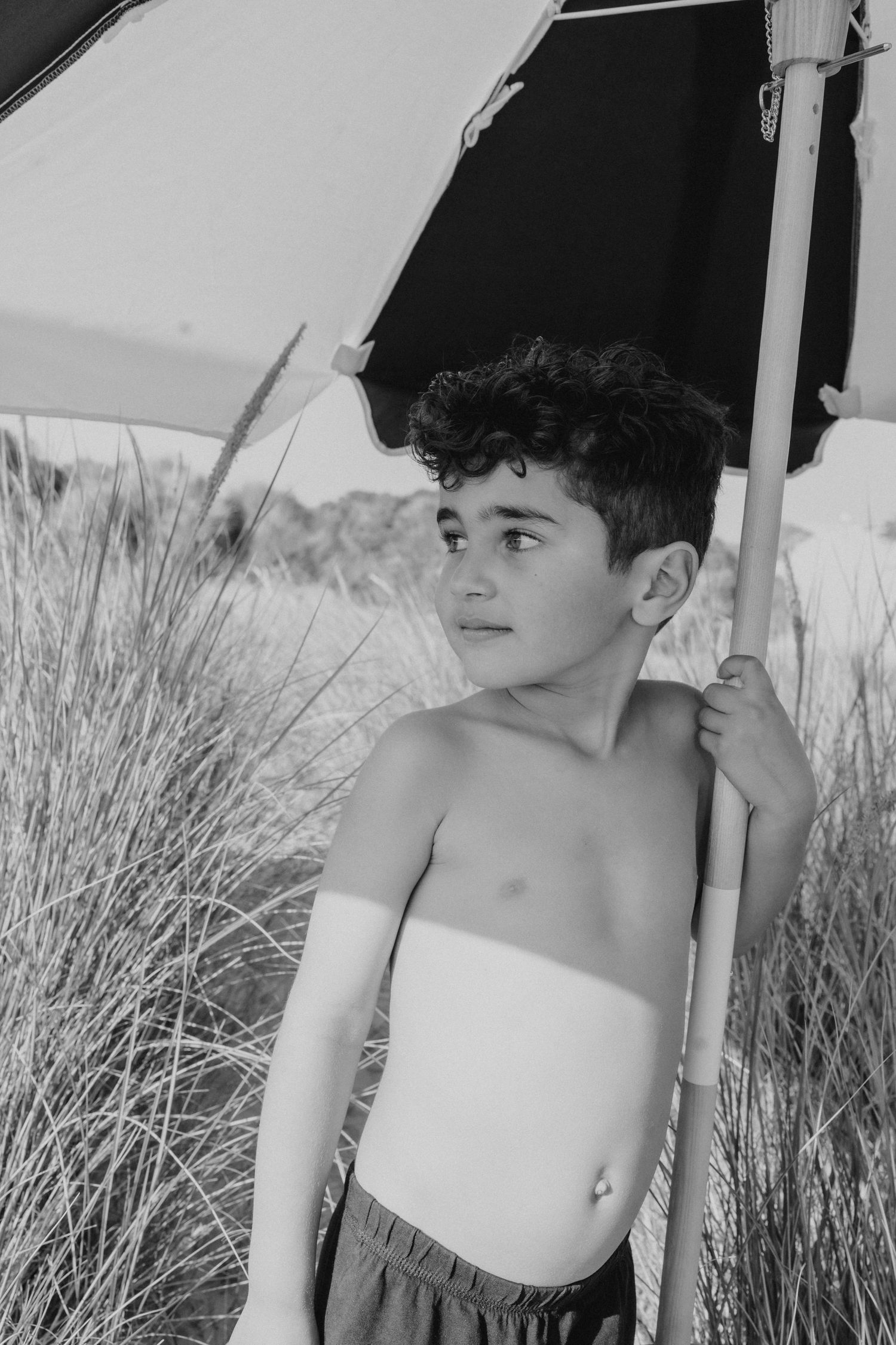 Black and white portrait under beach umbrella with dune grass in background.