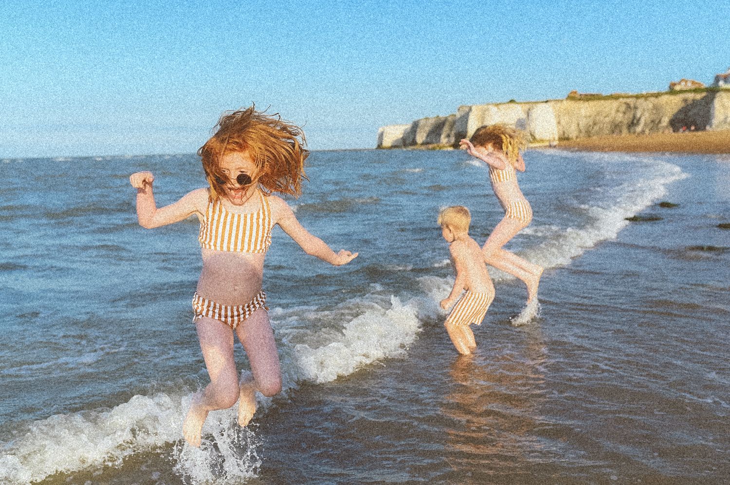 People splashing and playing in ocean waves on a sunny beach day.