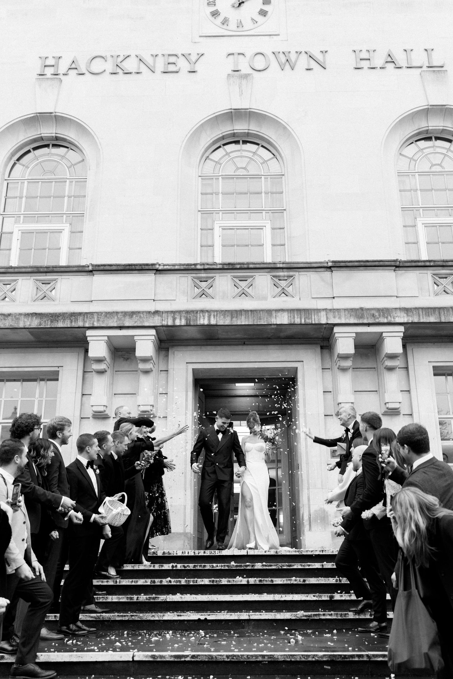 Wedding party gathered on steps of Hackney Town Hall for celebratory group photo.