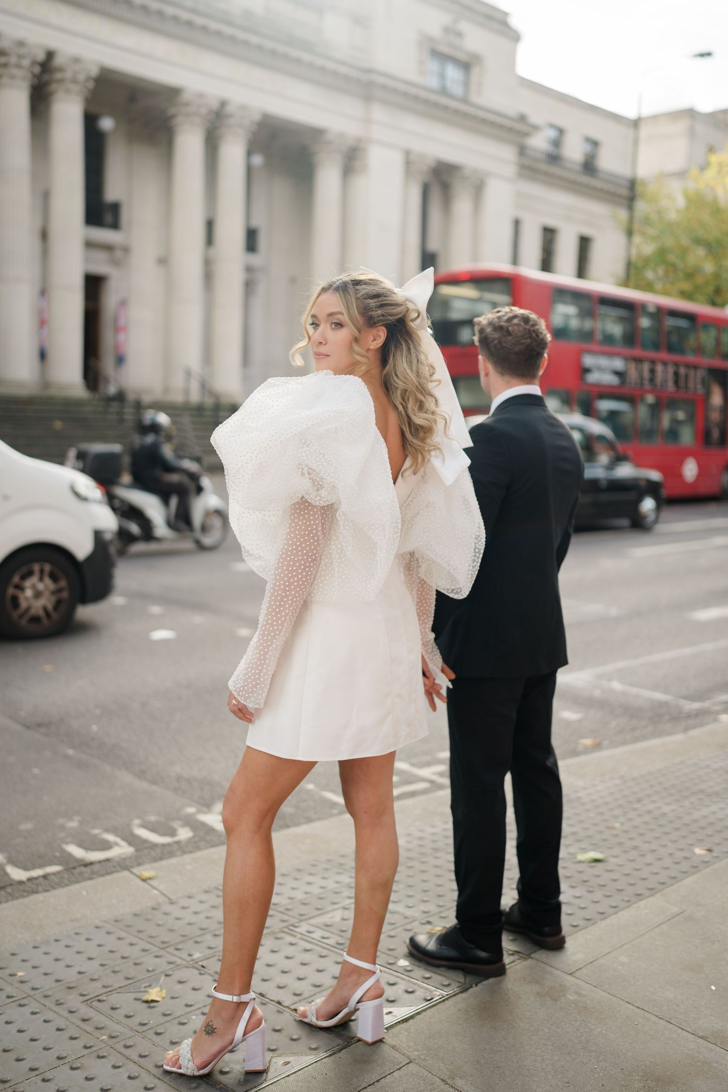 Playful wedding photo series showing a couple in white dress and black suit on a London sidewalk.