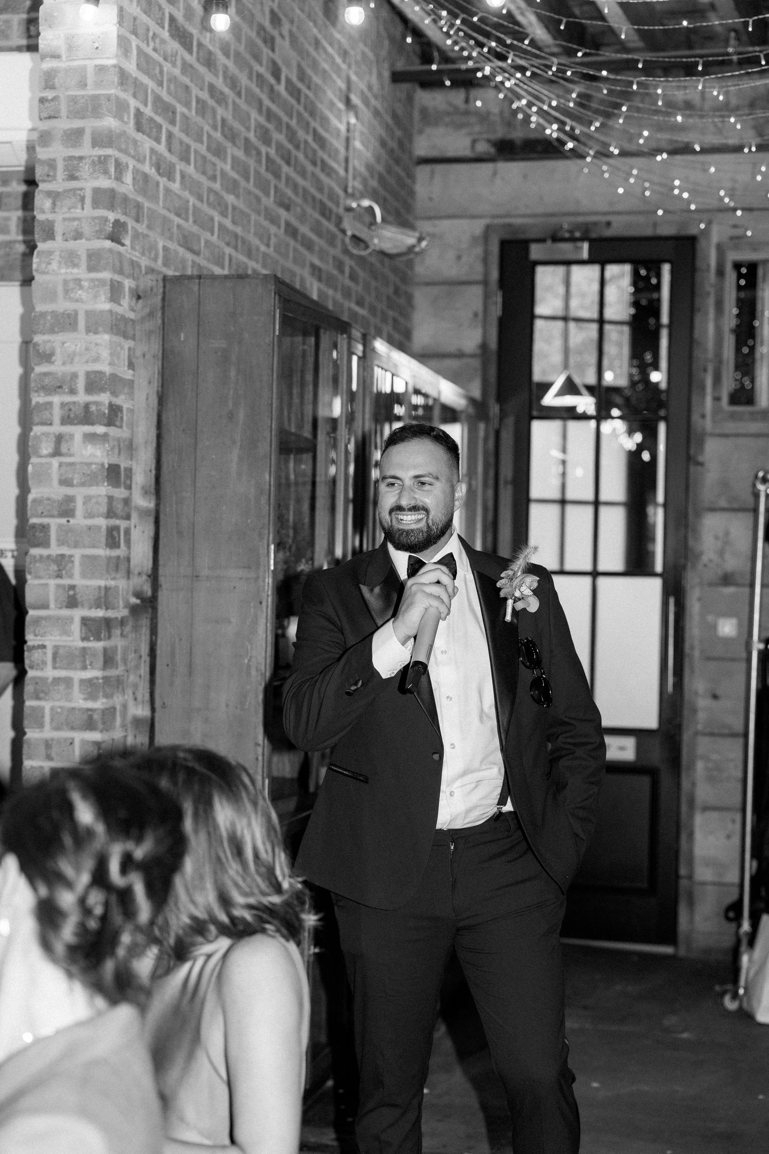 Wedding reception in industrial brick venue with string lights.