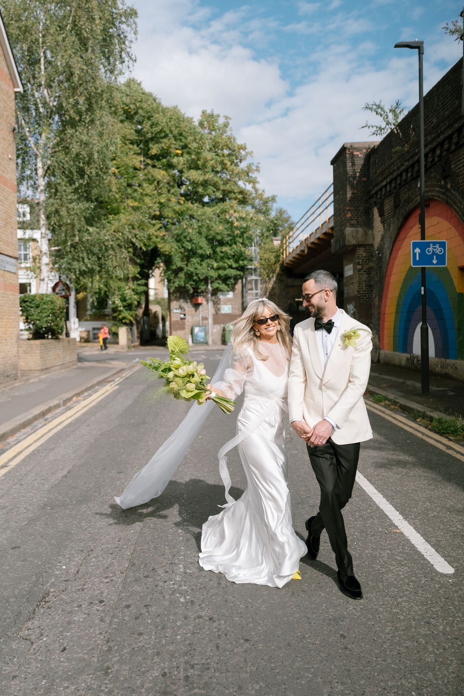 Wedding couple dancing and twirling on a street with buildings in the background.
