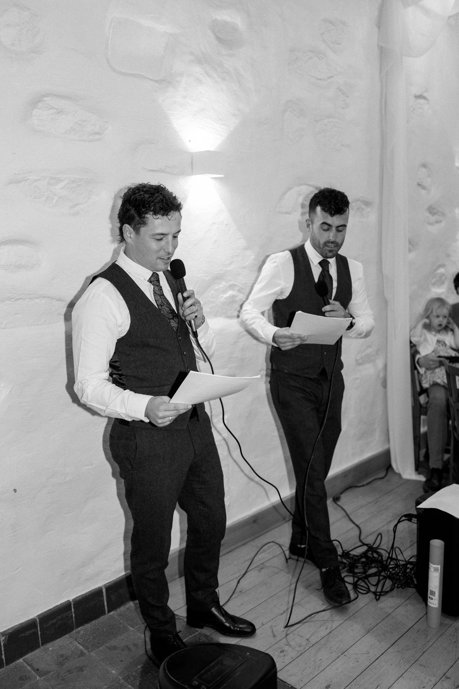 Black and white photo of speakers giving toasts at a wedding reception.