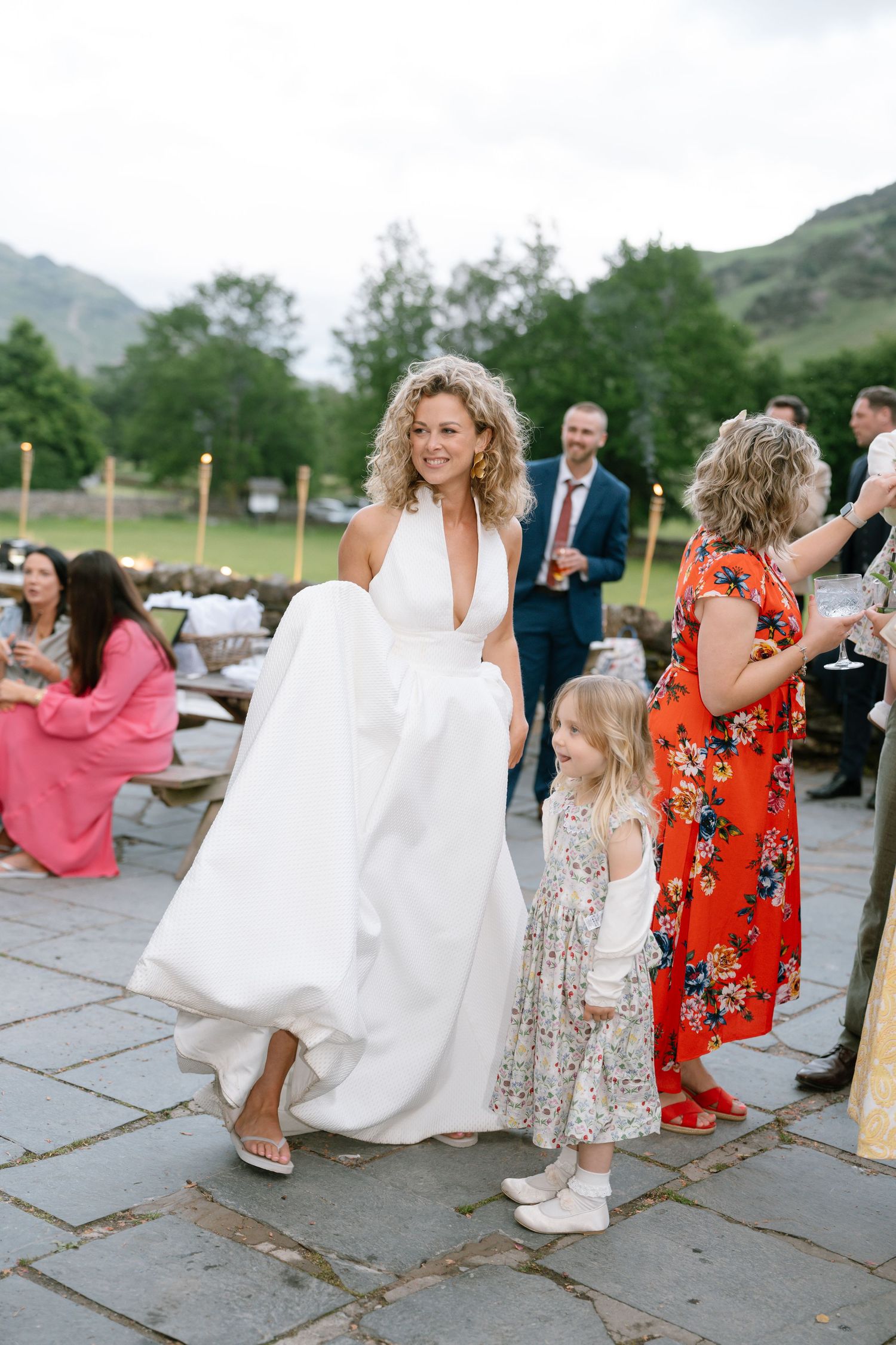 Wedding guests dance and celebrate on a stone patio with mountain scenery behind them.