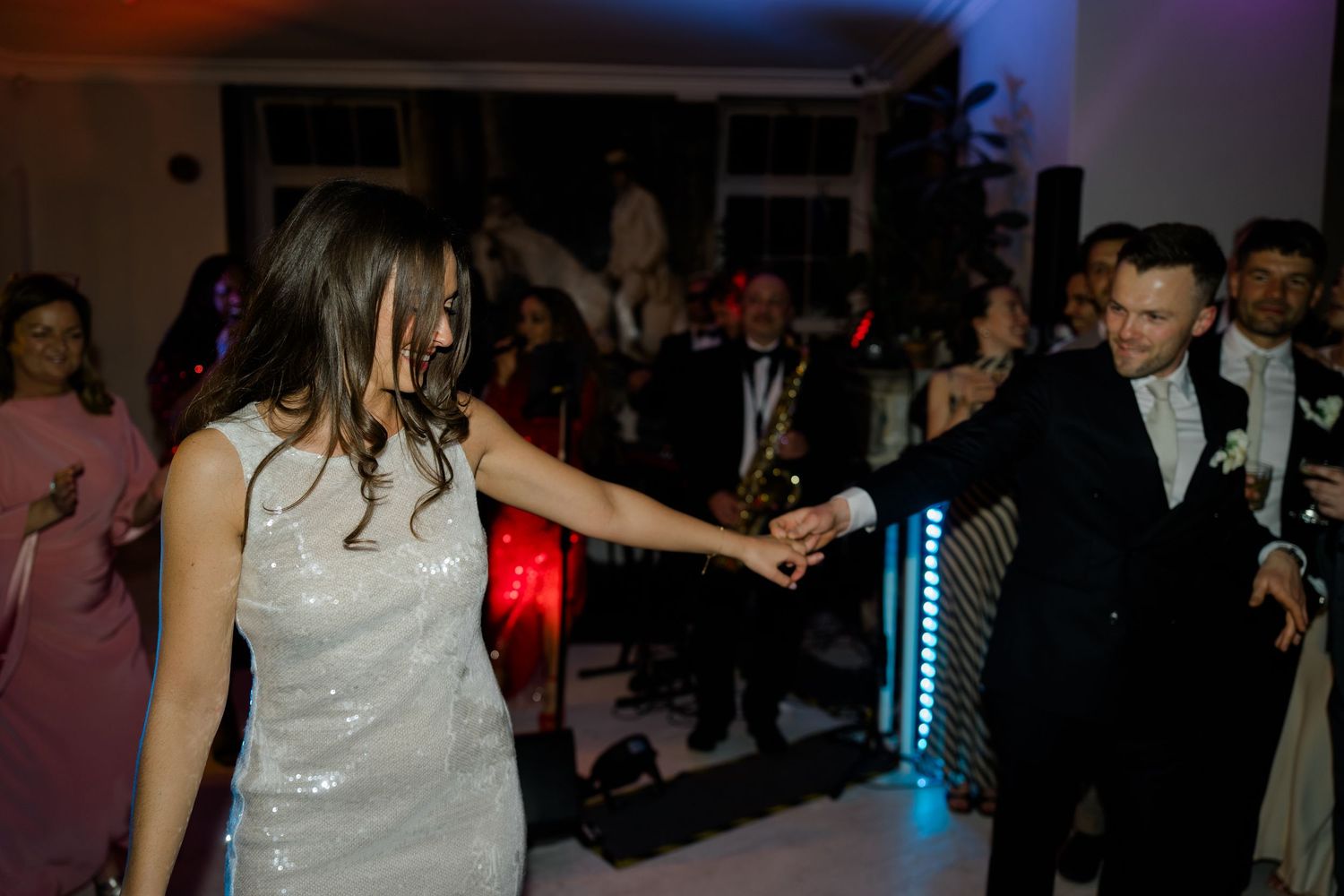 Bride and groom dancing together on the dance floor surrounded by guests at their wedding reception.