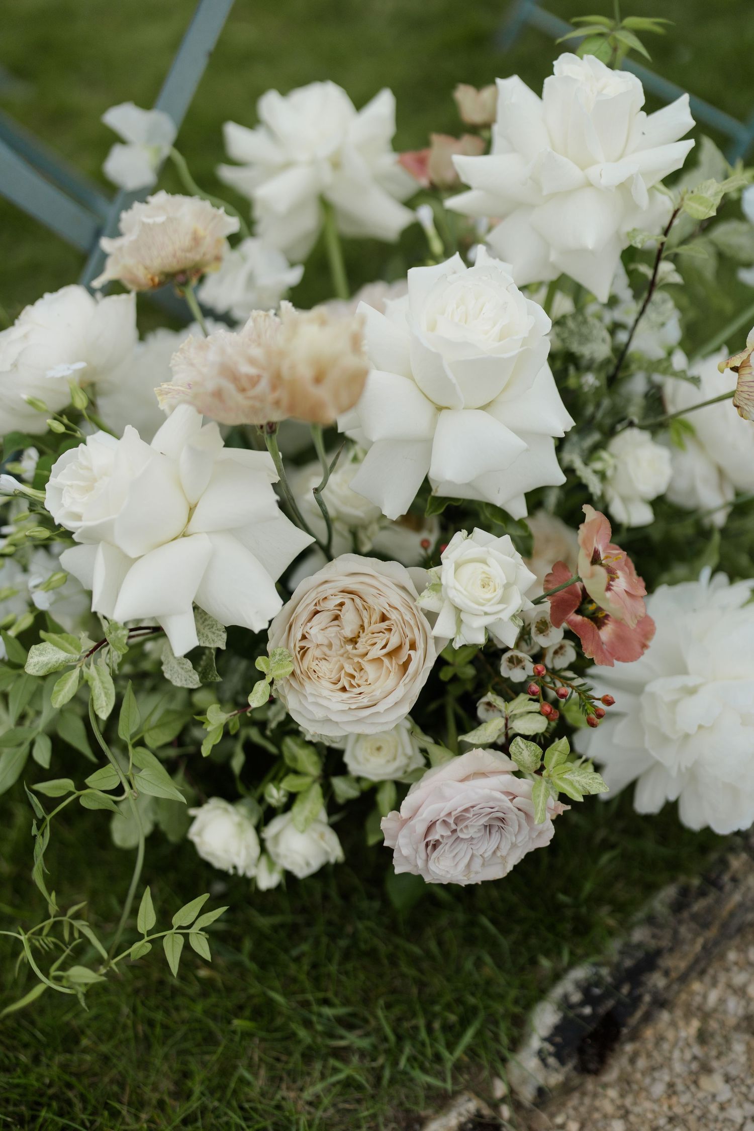 Elegant wedding floral arrangement featuring white roses, blush peonies, and greenery on a garden stone.